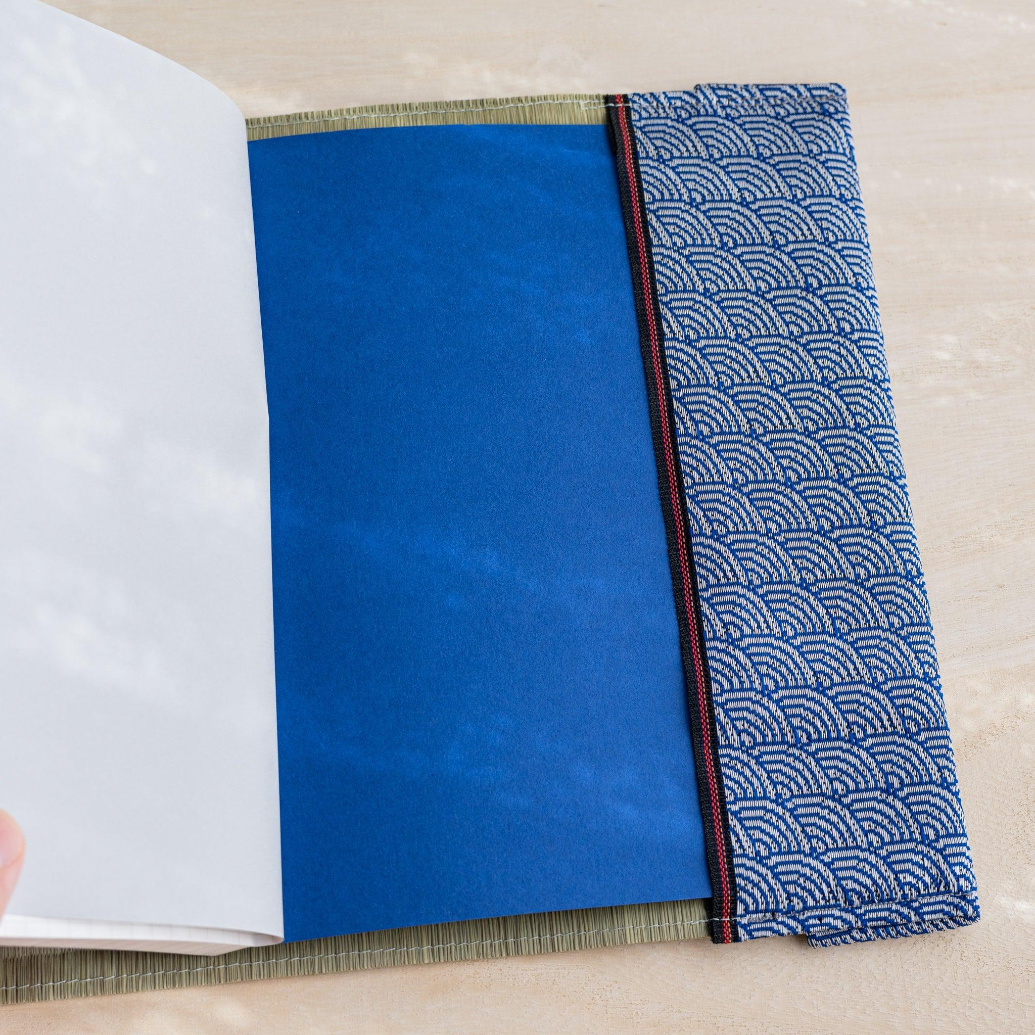 Angled view of tatami book cover interior with blue notebook cover and blue and white wave pattern fabric band