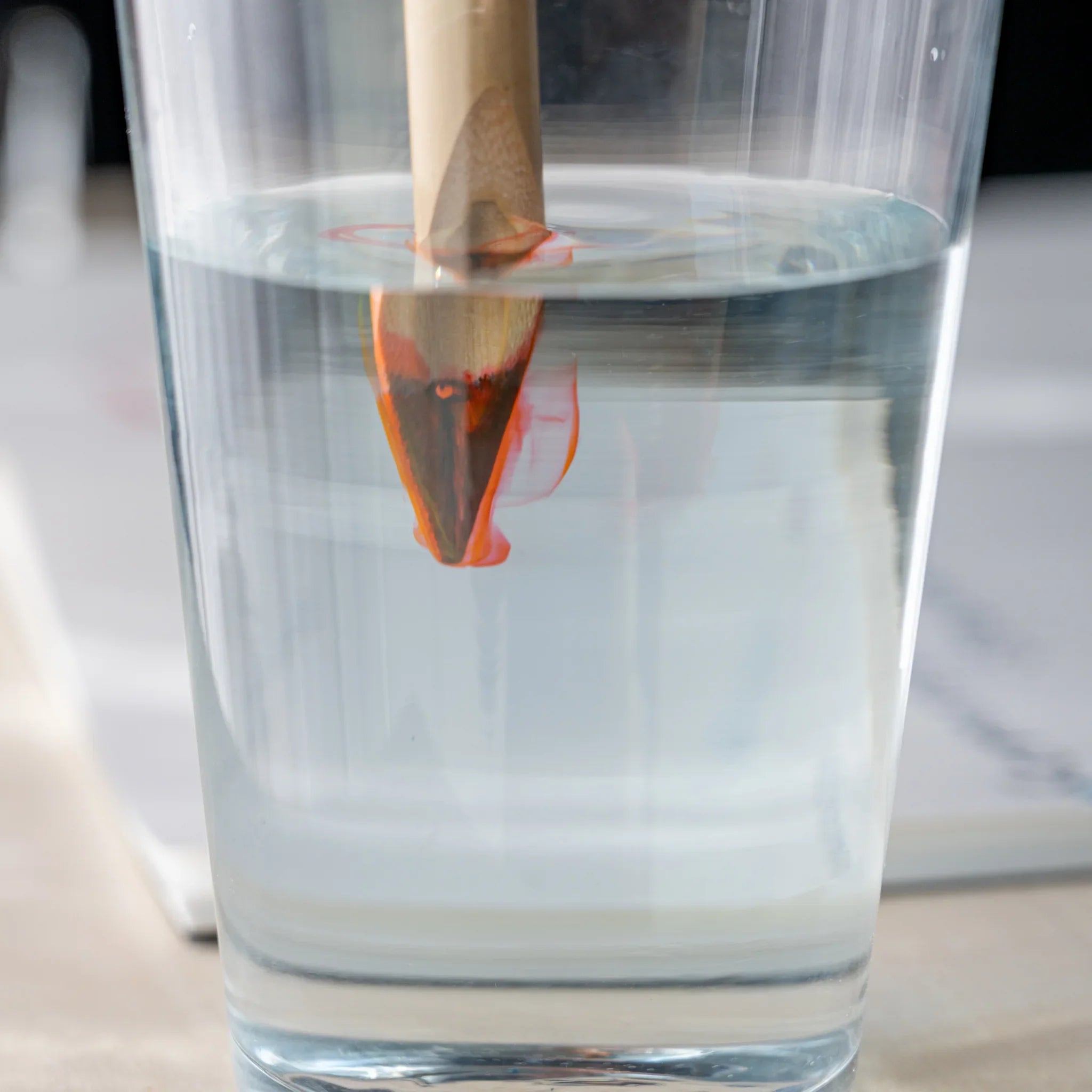 Boku-Undo bamboo dip pen nib submerged in glass of water with red ink dissolving and swirling around it