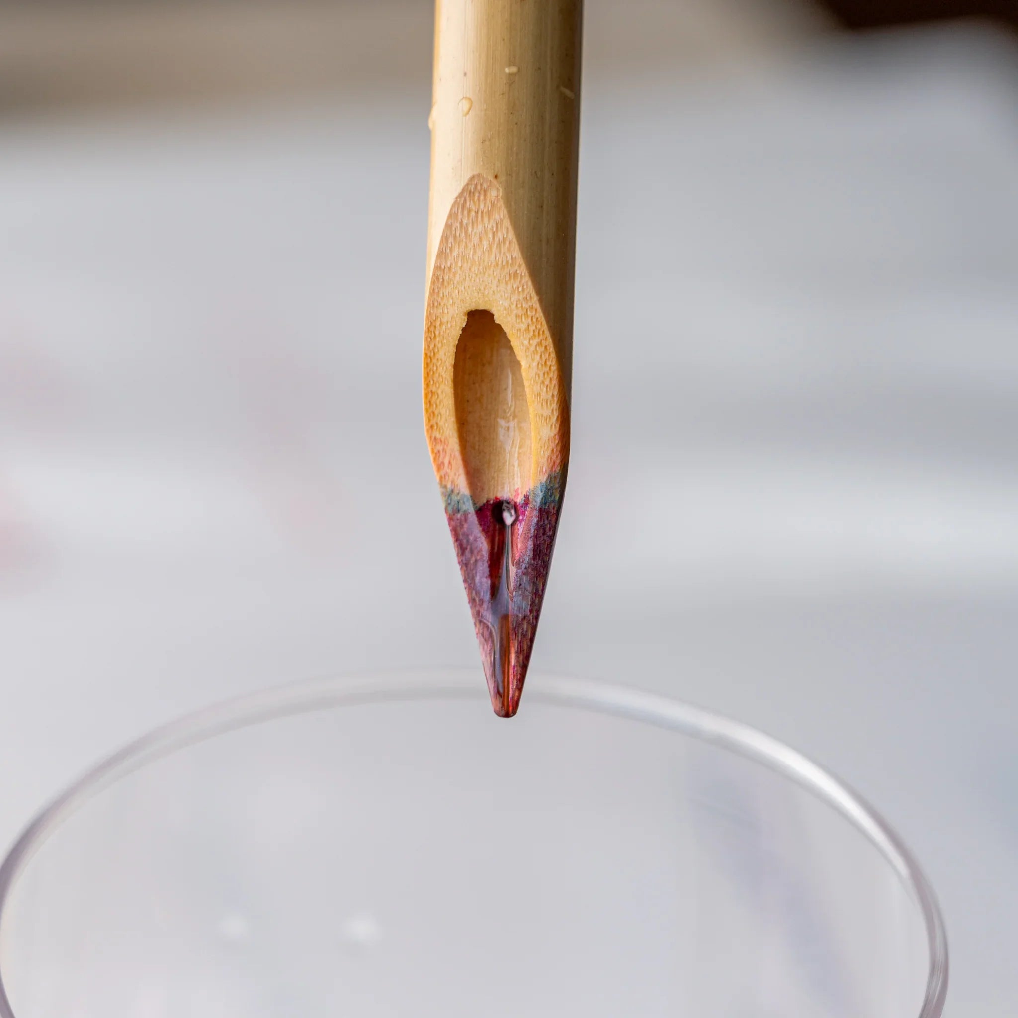 Close-up of Boku-Undo bamboo dip pen nib above glass rim showing residual mixed ink after rinsing