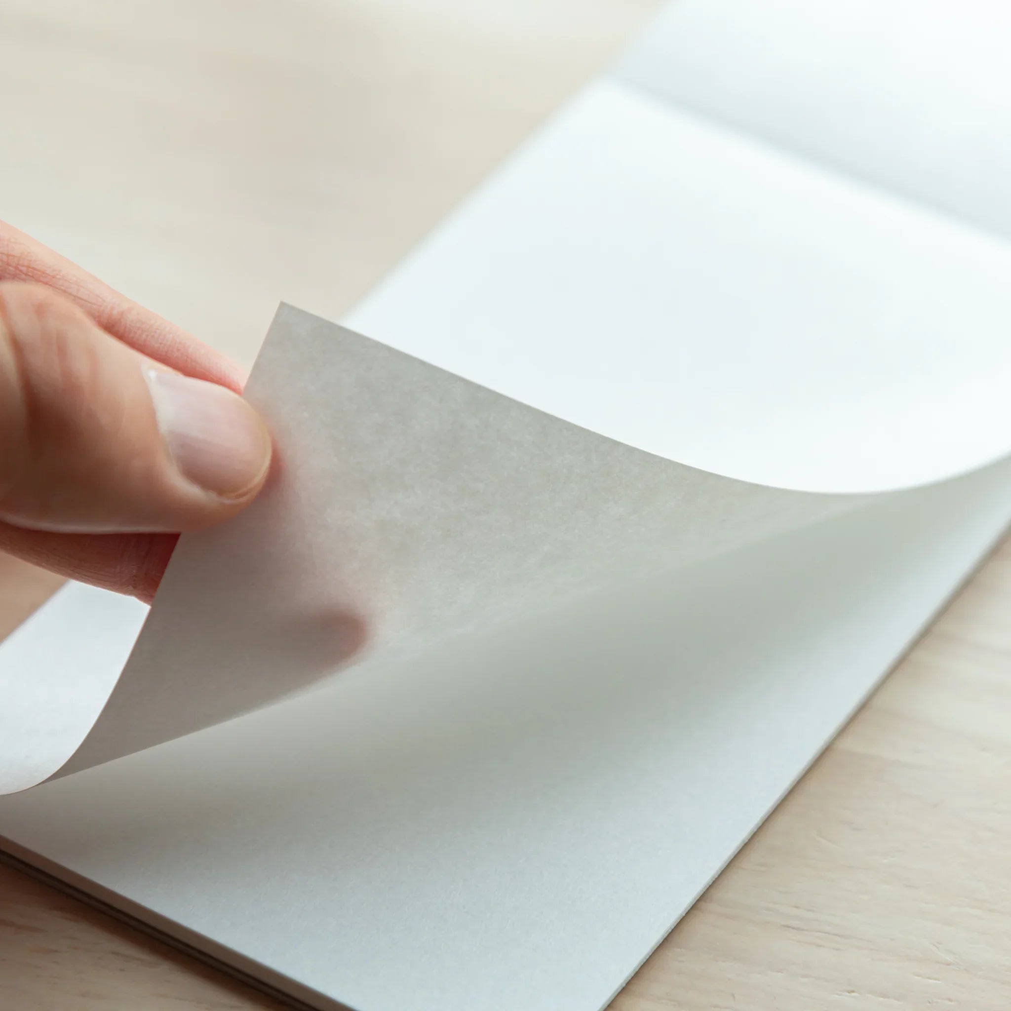 Hand peeling a page from Bullet Jotter writing pad, showing light-tinted Sheep Clouds Bond paper texture and page separation
