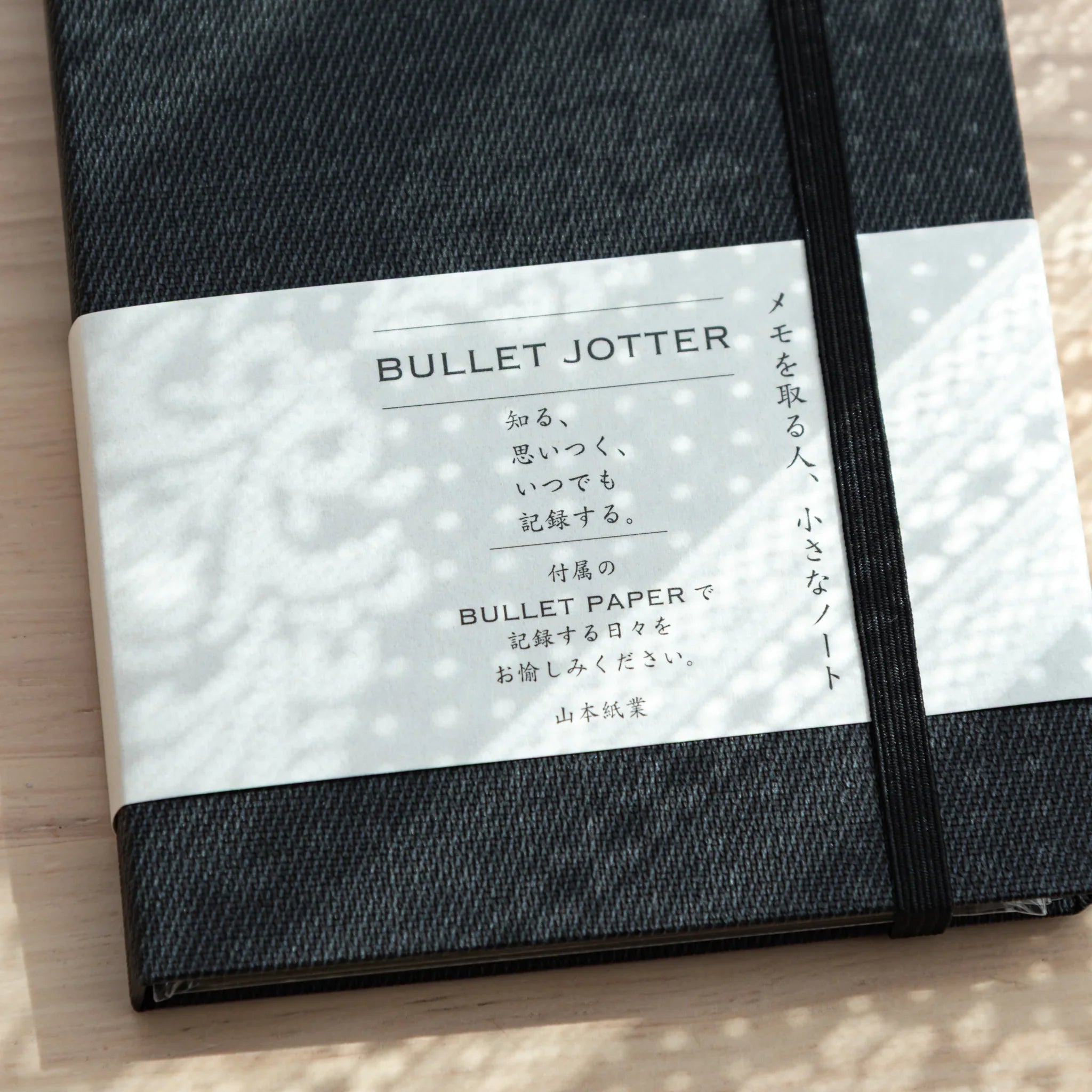 Close-up of Bullet Jotter black gabardine cover belly band: BULLET JOTTER title, Japanese description, black elastic band