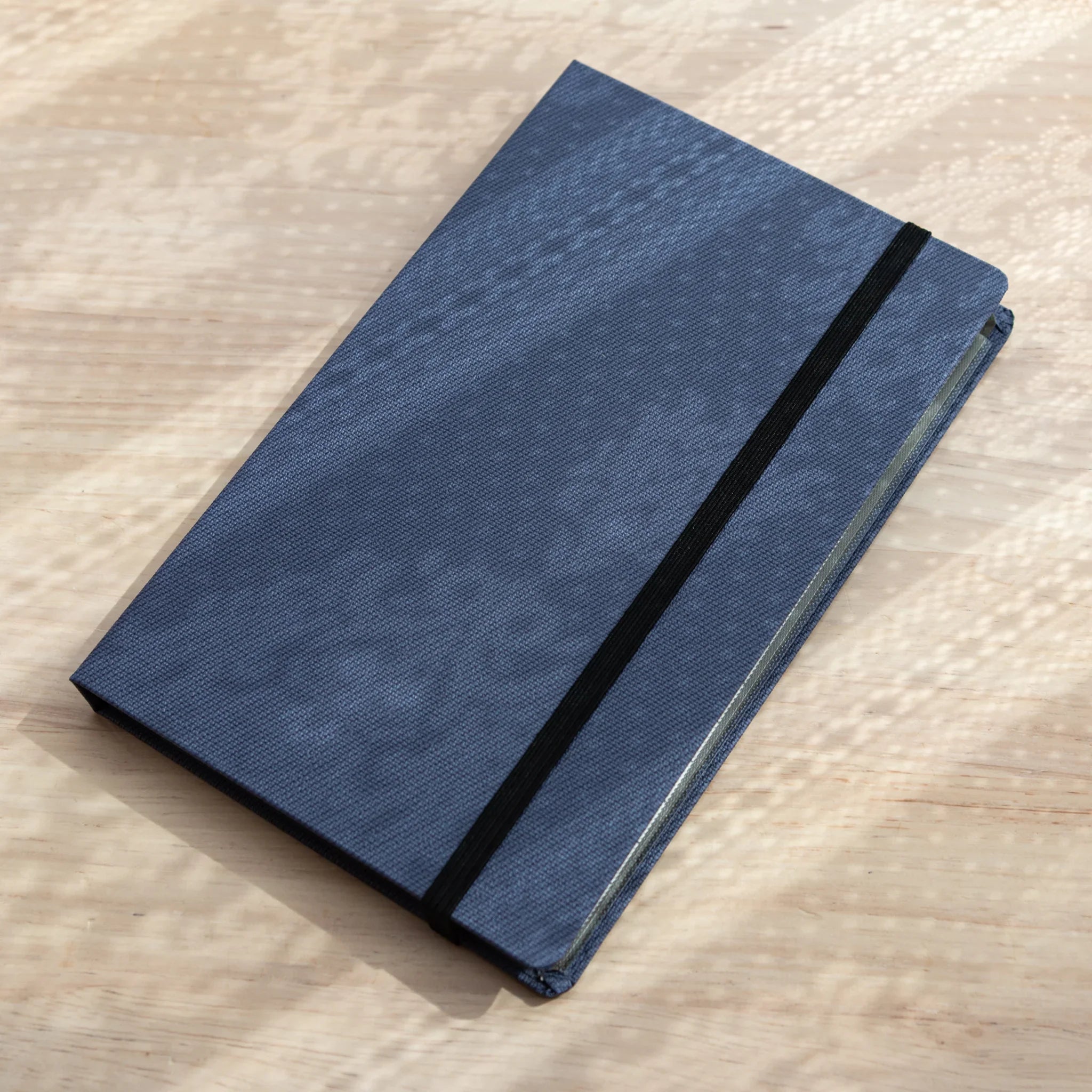 Bullet Jotter royal blue gabardine cover closed on light wood at angle, black elastic band across front, pad edges visible