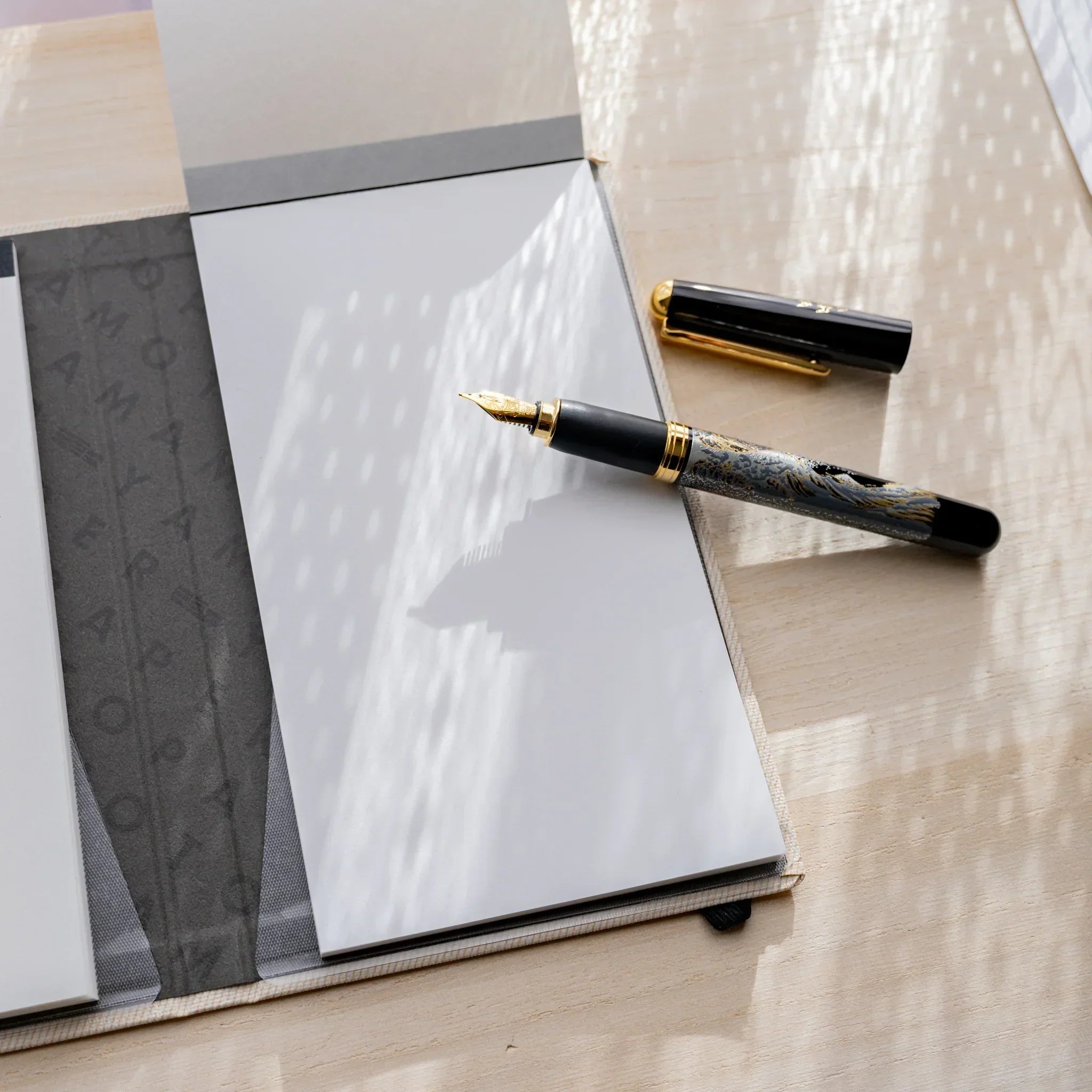 Yamamoto Paper Canopus Bullet Paper No.2 notepad in a notebook cover beside a Japanese fountain pen.
