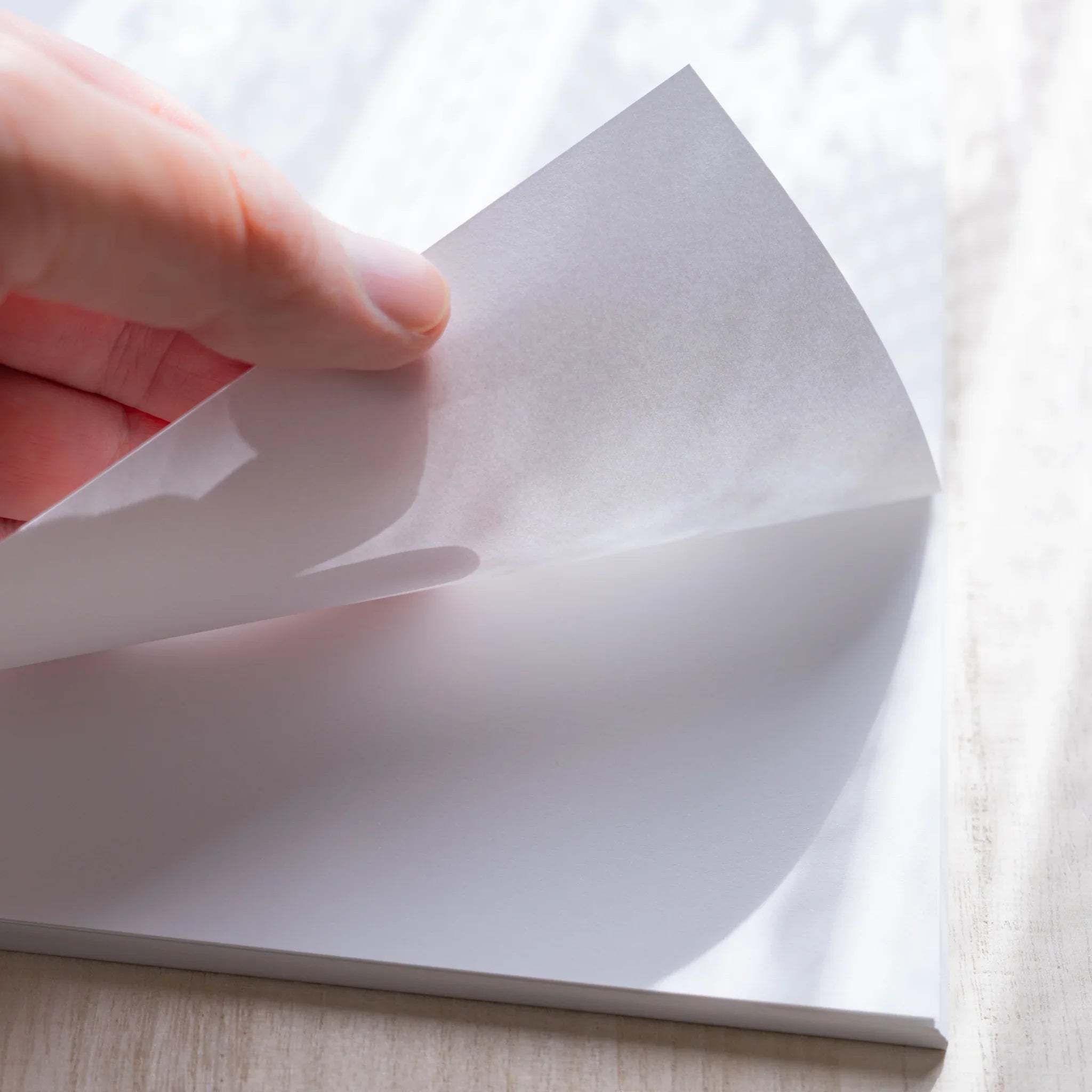 Hand peeling a top sheet from a Yamamoto Paper Canopus A4 loose leaf paper stack.