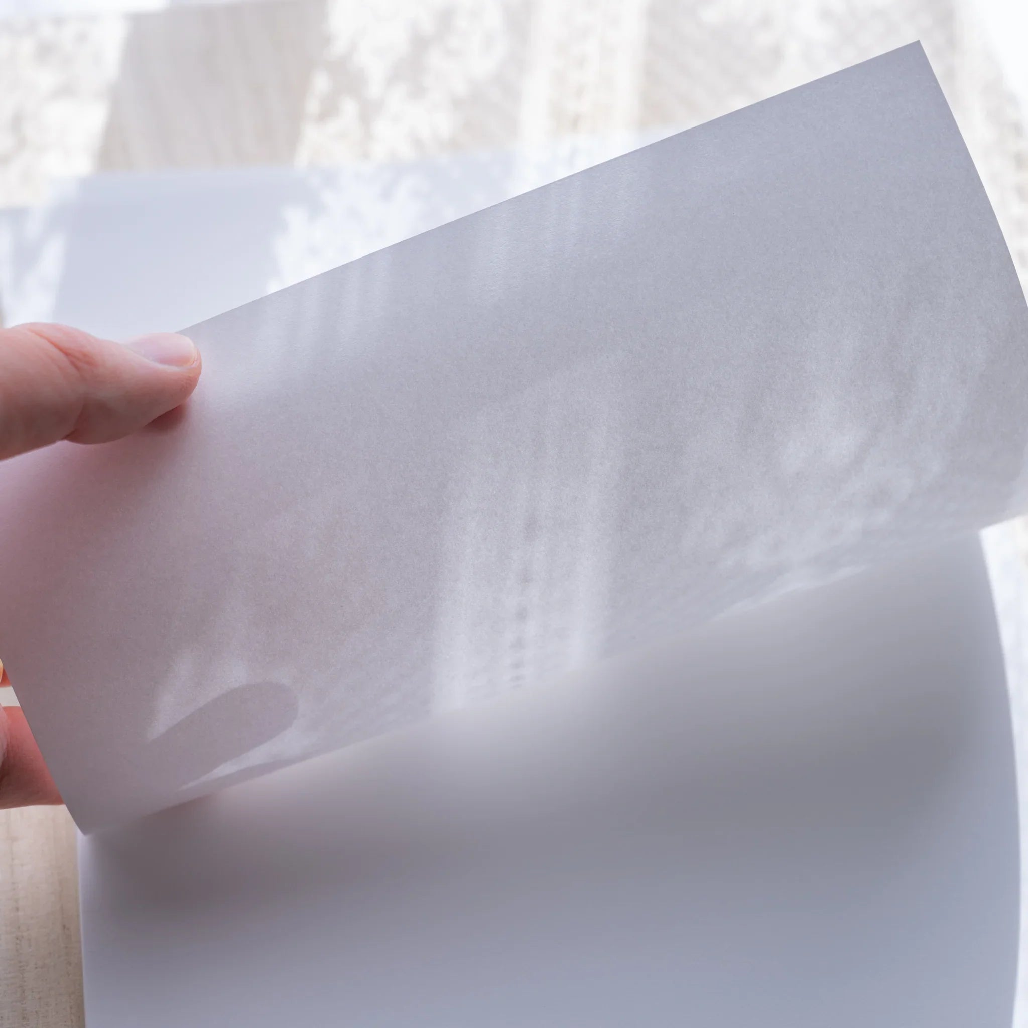 Hand holding a Yamamoto Paper Canopus A4 sheet up to light showing paper translucency.