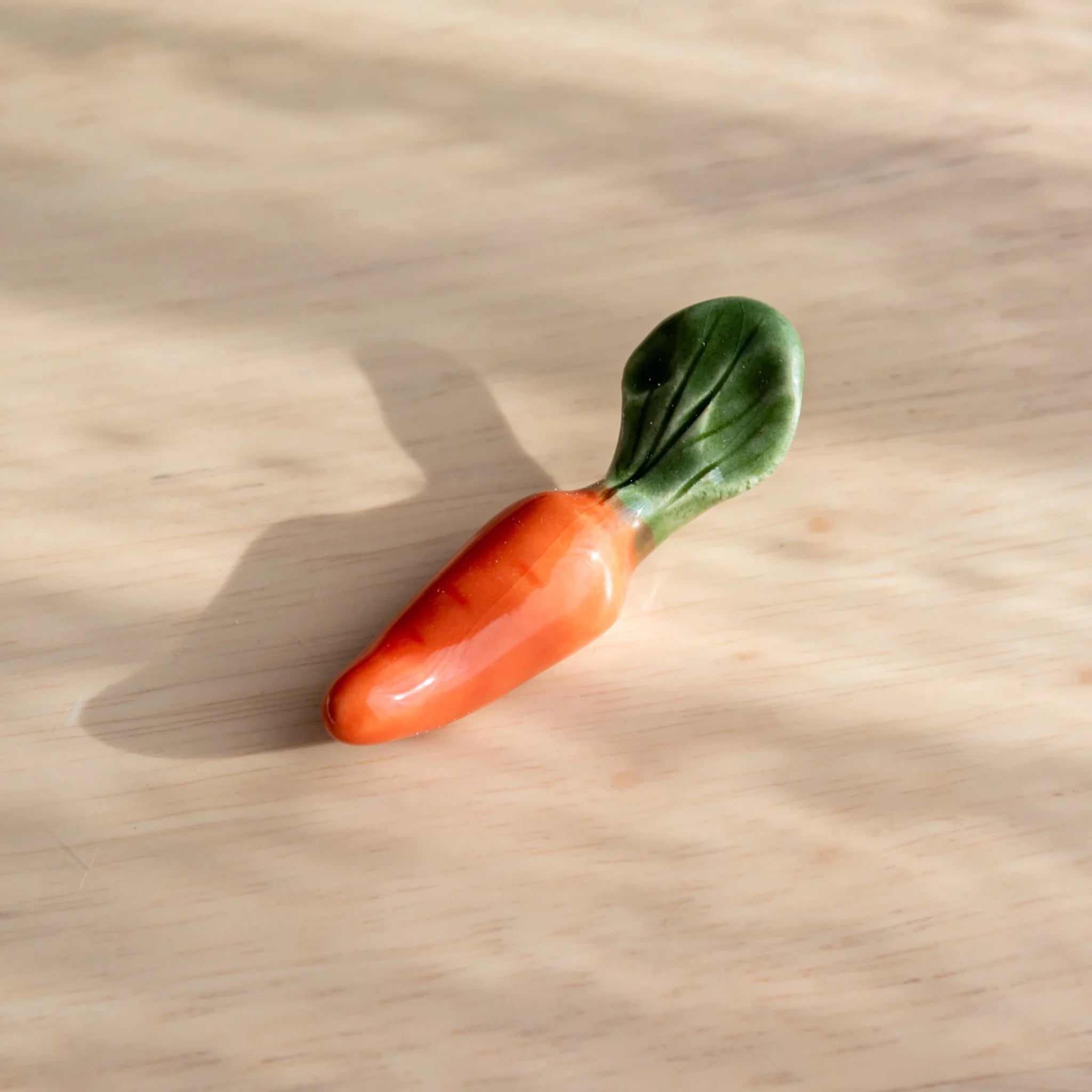 Orange Japanese carrot handcrafted ceramic pen rest with realistic vegetable proportions and grooved close shot