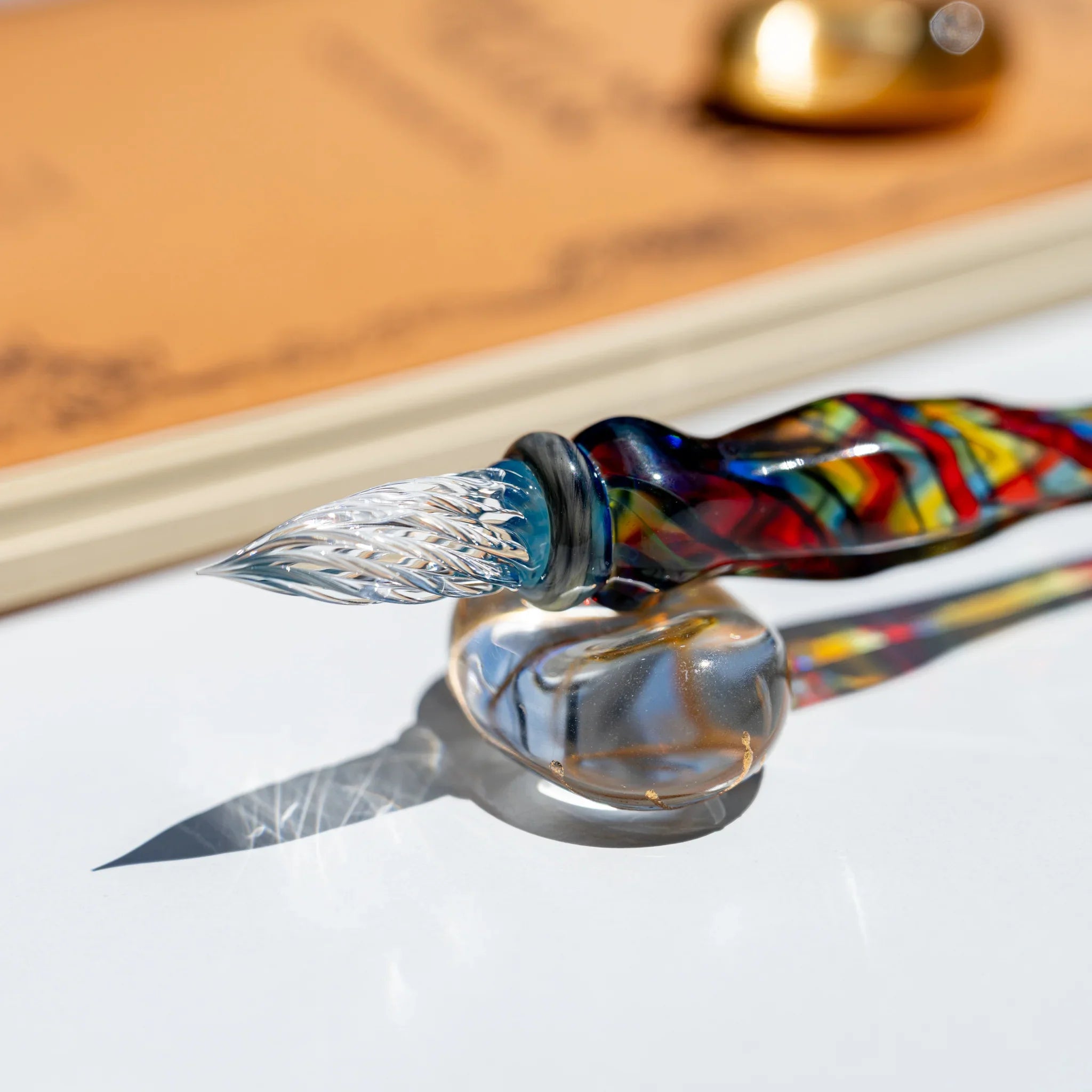 Close-up of the clear twisted glass nib with an aqua collar, resting on a round clear glass pen rest