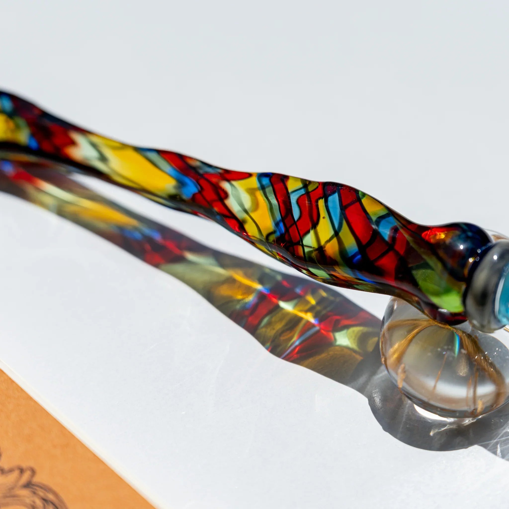 Close-up of the twisted stained-glass mosaic shaft in red, yellow, blue and green outlined with thin black lines