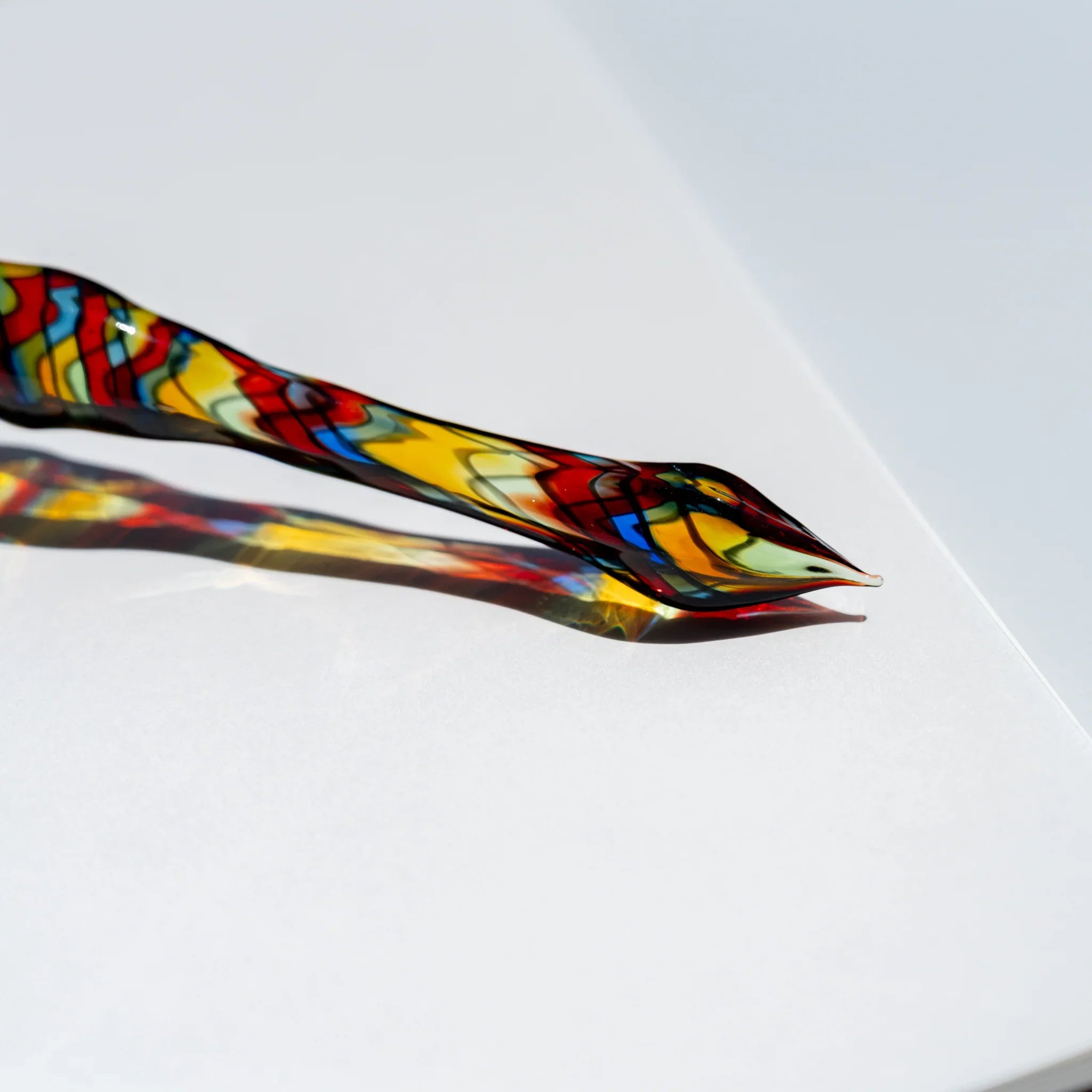Close-up of the pointed glass writing tip, stained-glass mosaic in red, yellow, blue and green with black outlines