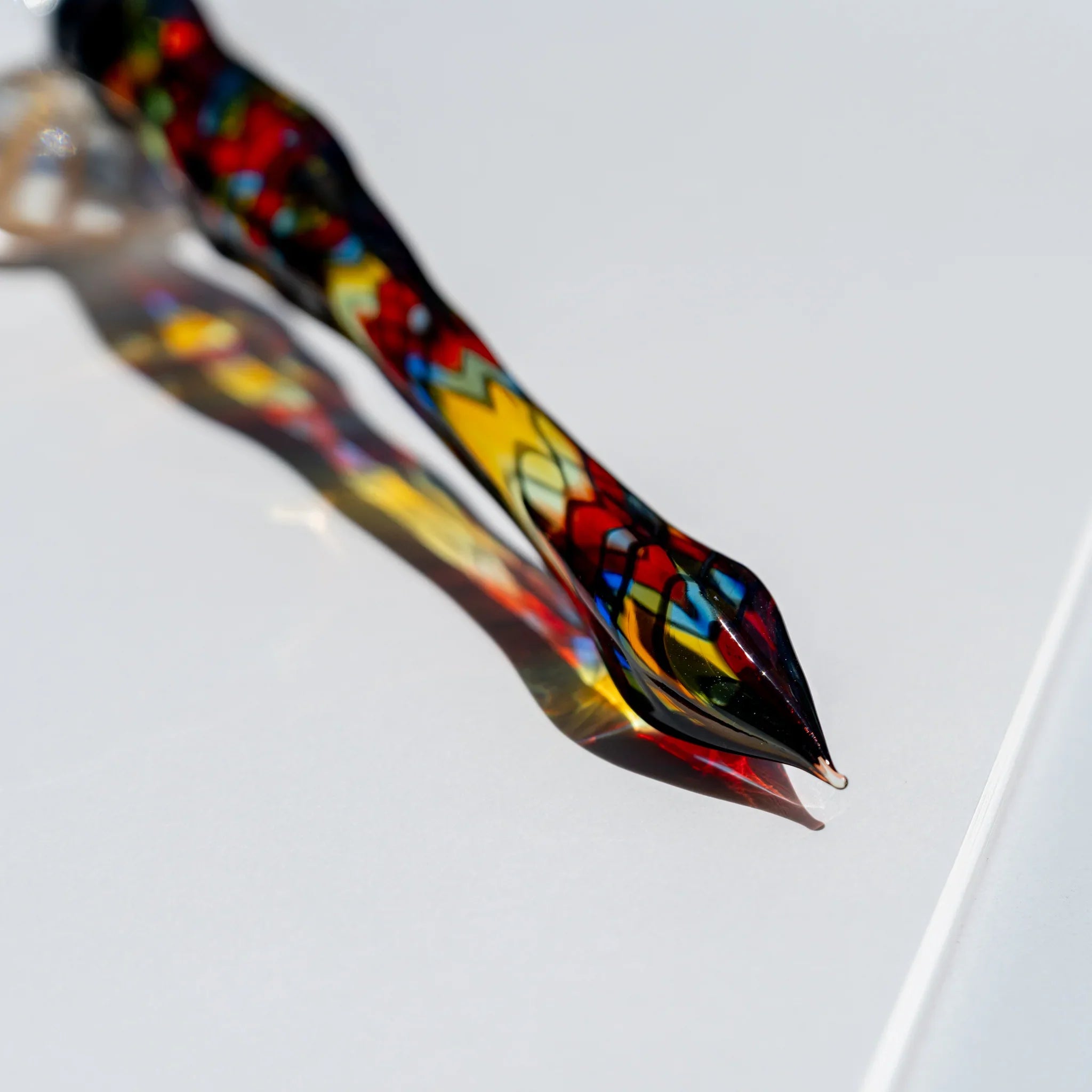 Macro of the tapered glass pen tip showing a grid mosaic of red, yellow, blue and green panes with black lines