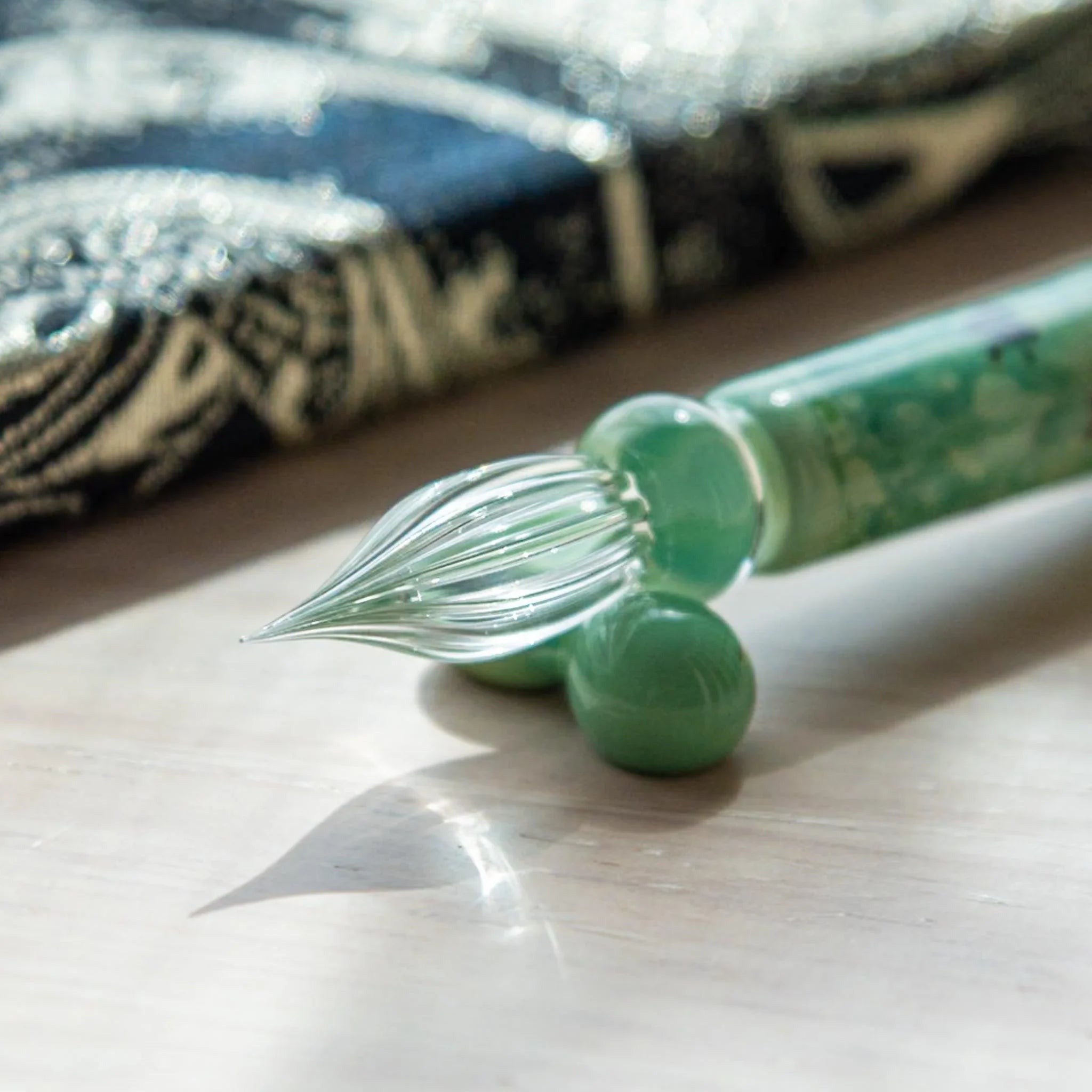 Display of emerald chidori glass dip pen featuring dark plover bird pattern with glass nib and pen rest holder