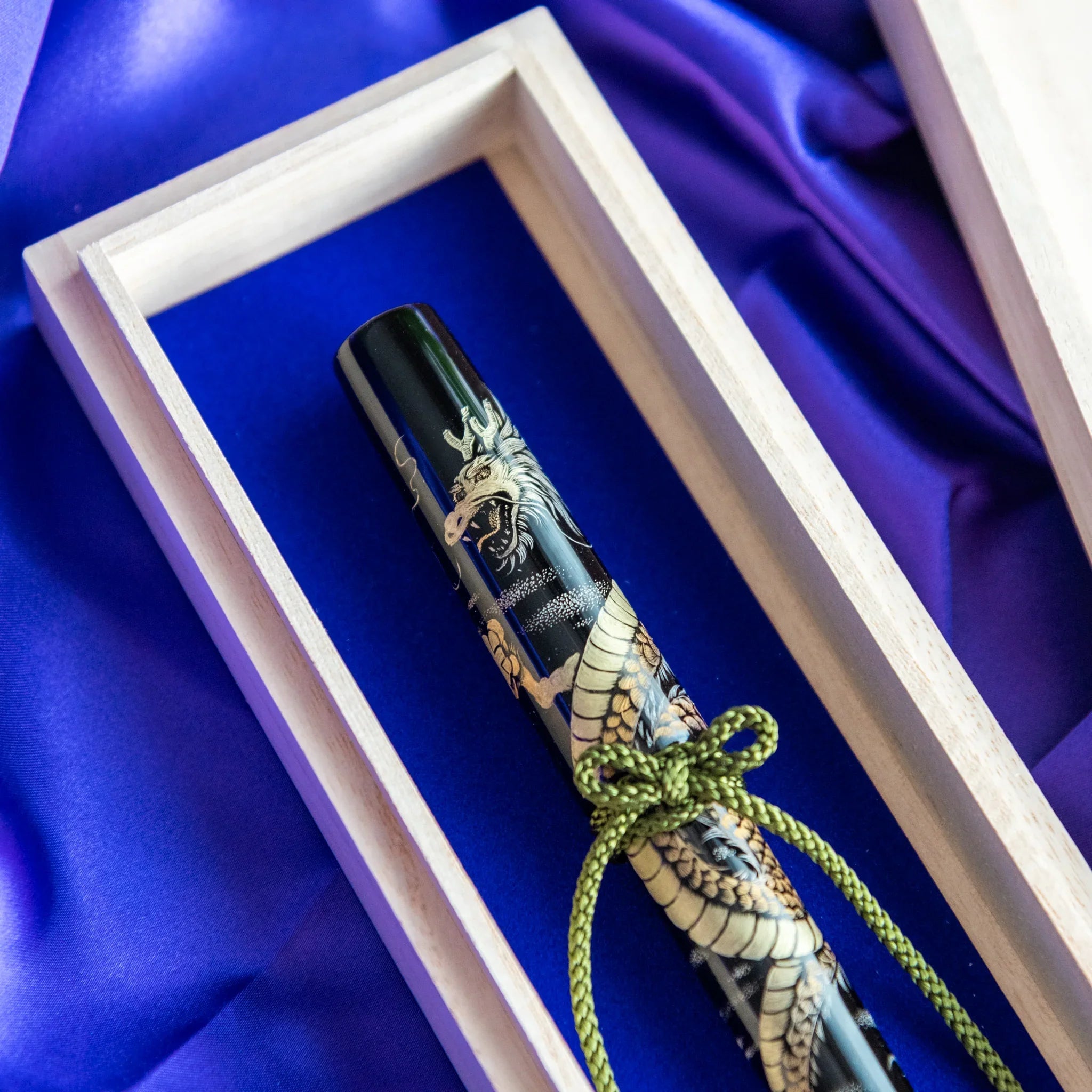 Open wooden box revealing Chinkin Dragon pen with gold tassel and blue silk lining showing product quality and design details