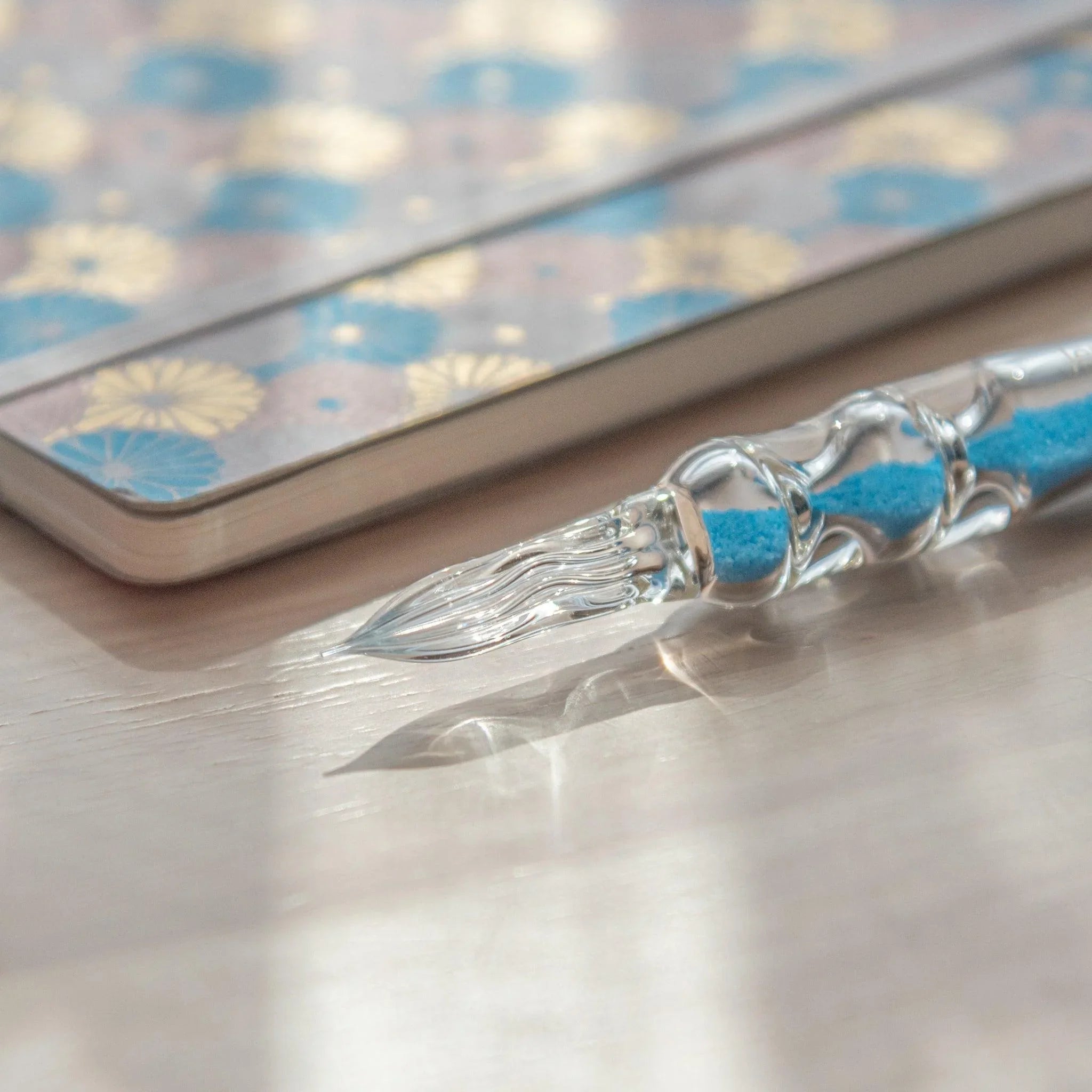 Cote d'Azur Hourglass Glass Dip Pen close-up showing three bulbous glass sections with vibrant blue gradient effect