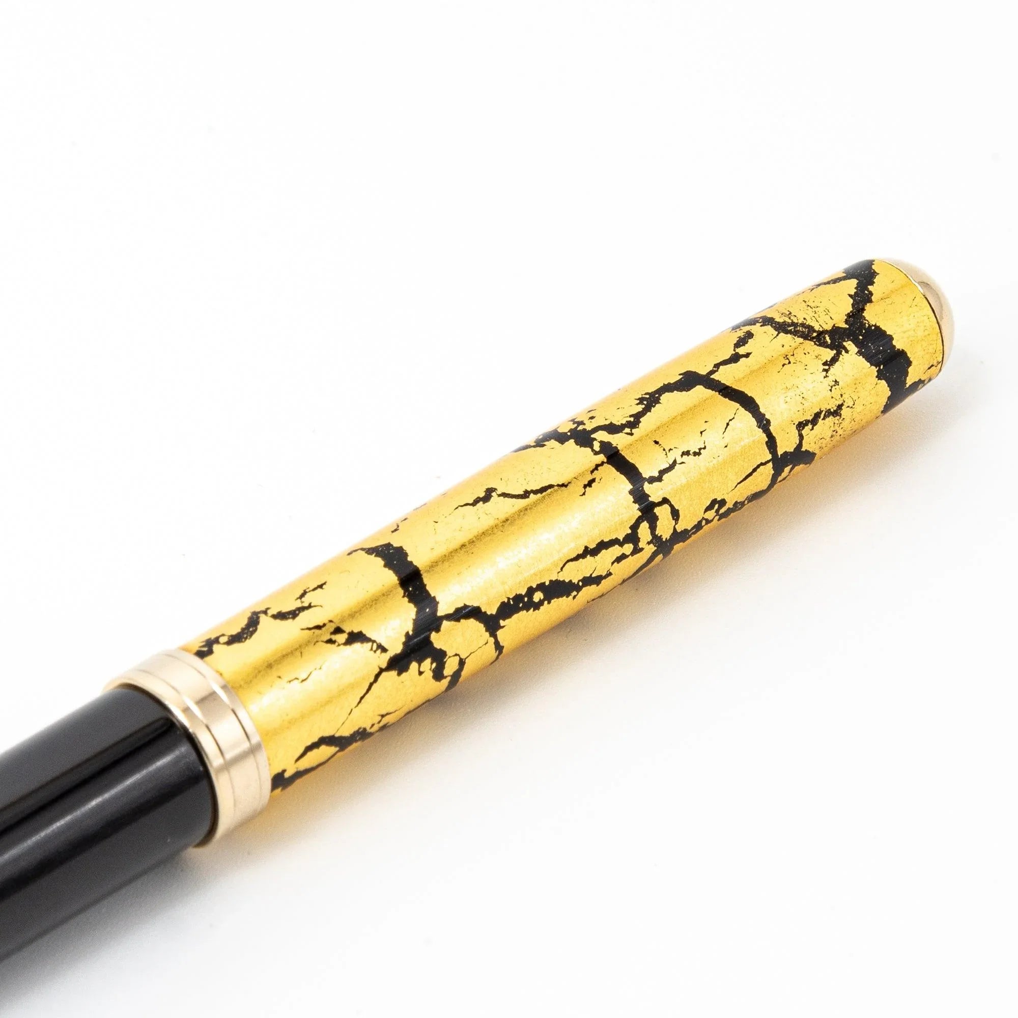 Japanese black ballpoint pen uncapped with gold clip and bands, gold crackle cap displayed separately shown