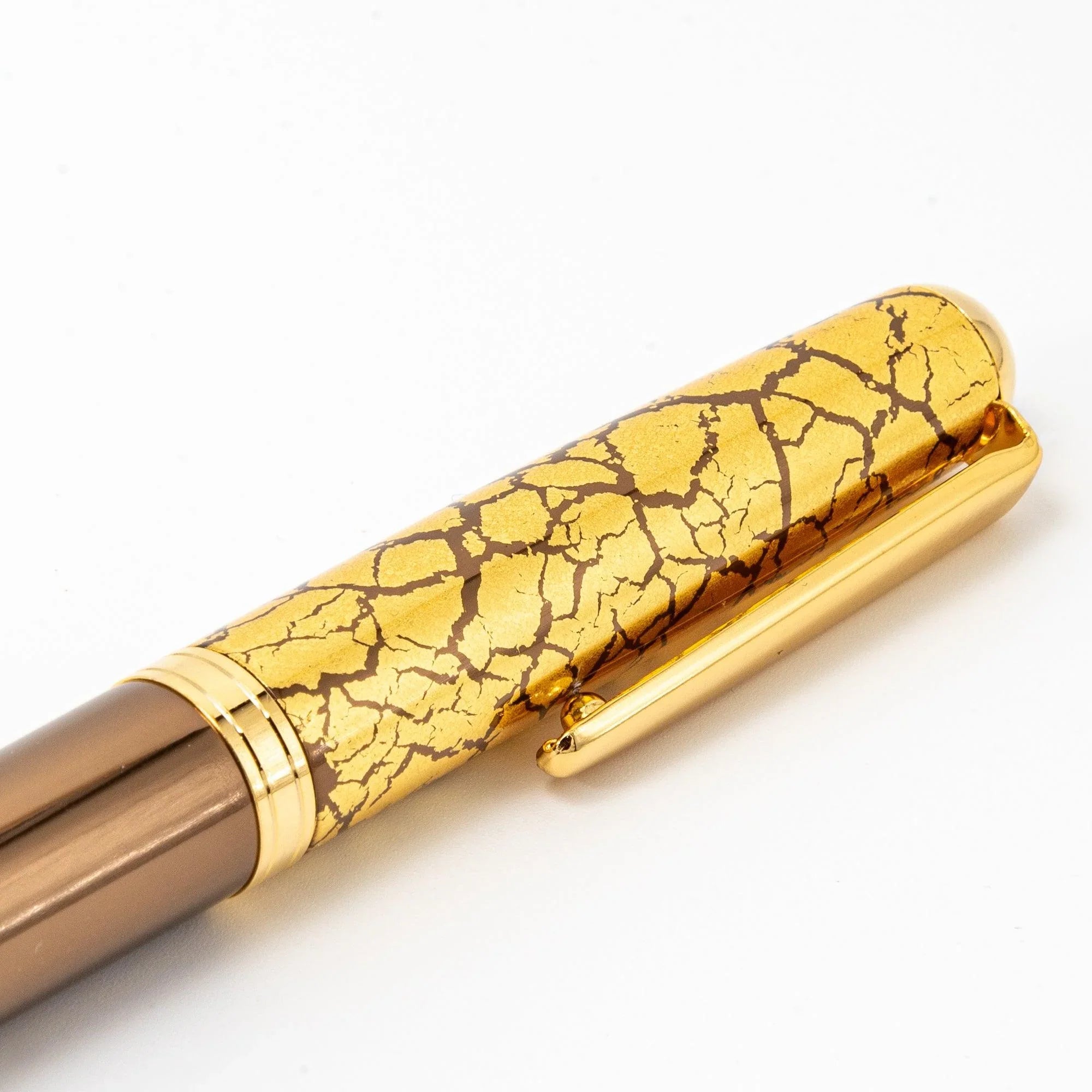 Brown lacquer fountain pen with gold leaf crackle pattern visible on uncapped barrel in detailed view