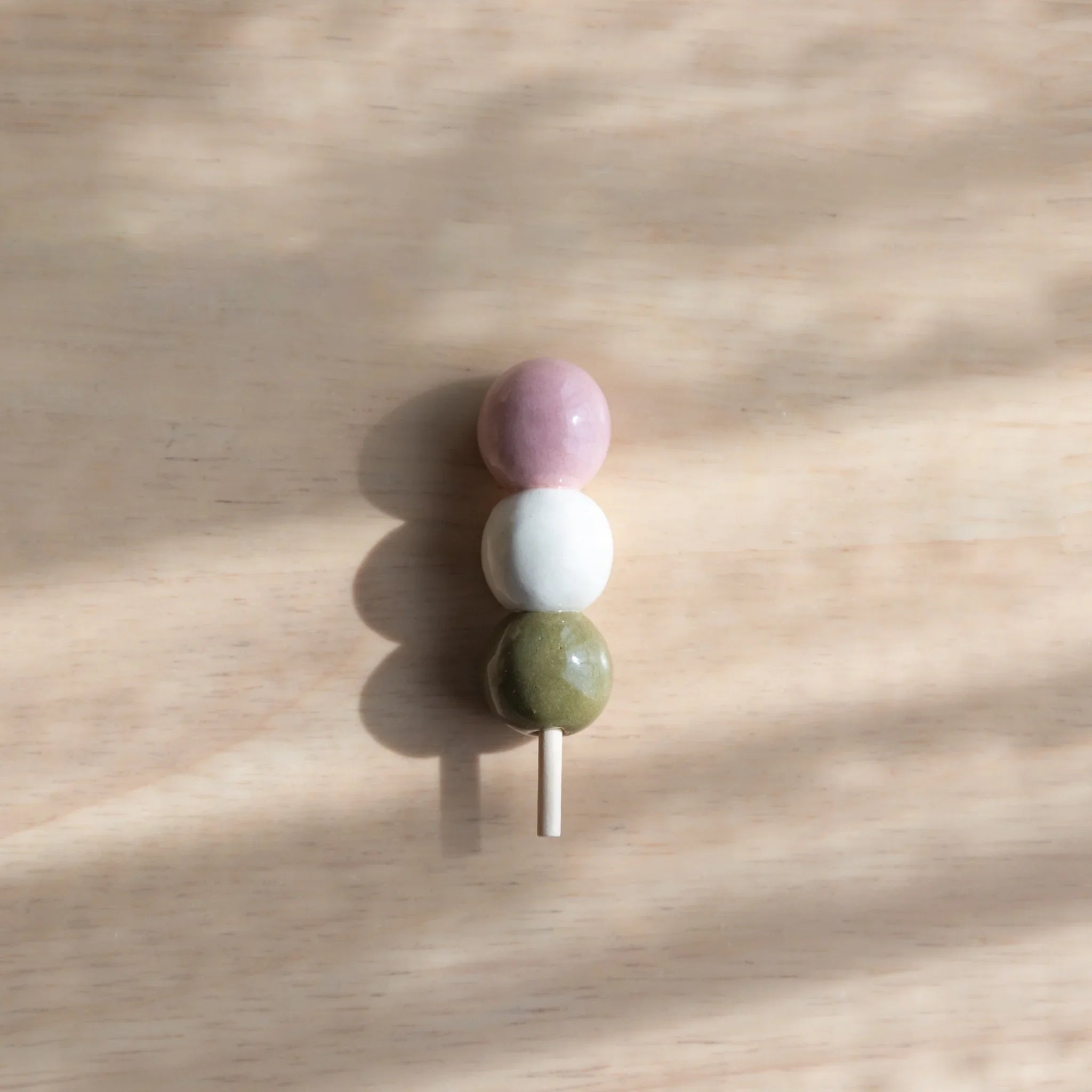 Colorful dango handcrafted pen rests with orange, white and brown ceramic spheres on wooden stick support detail