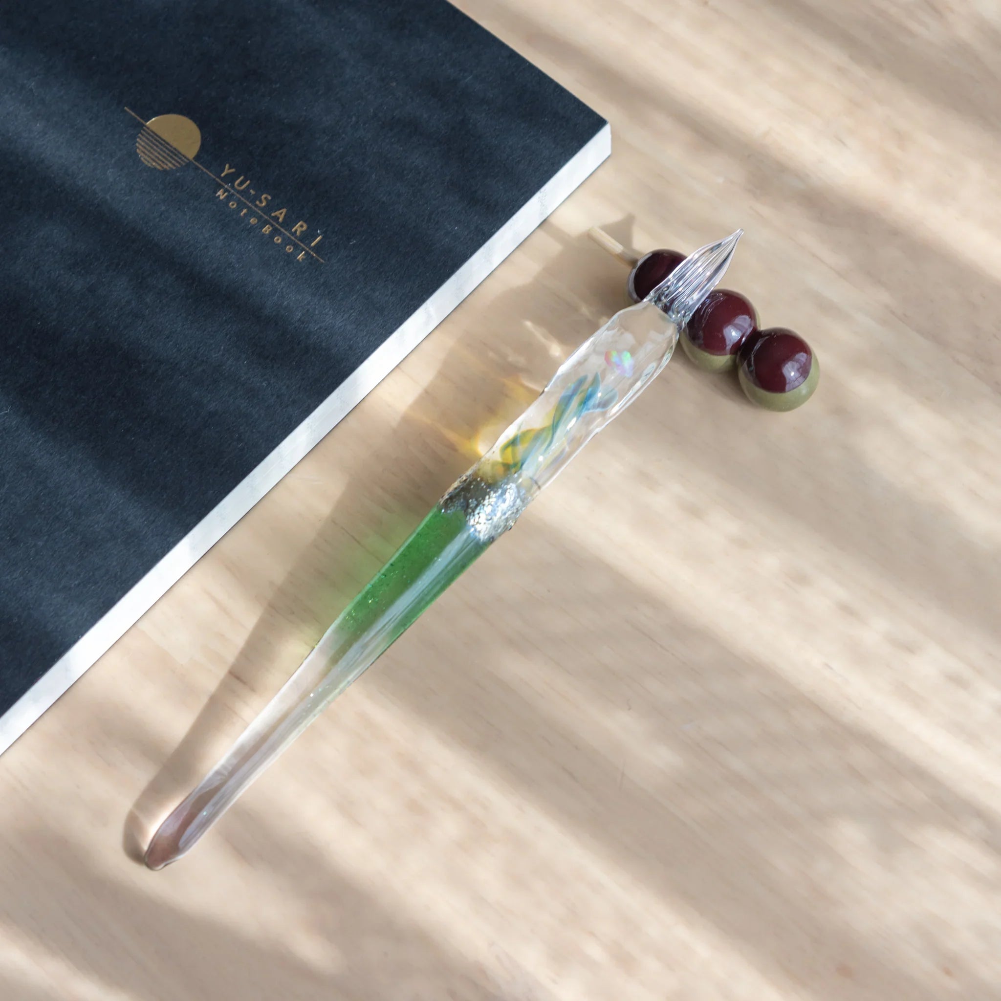 Orange and white dango pen rest with three beads arranged vertically on clear glass stick with bead spacers shine