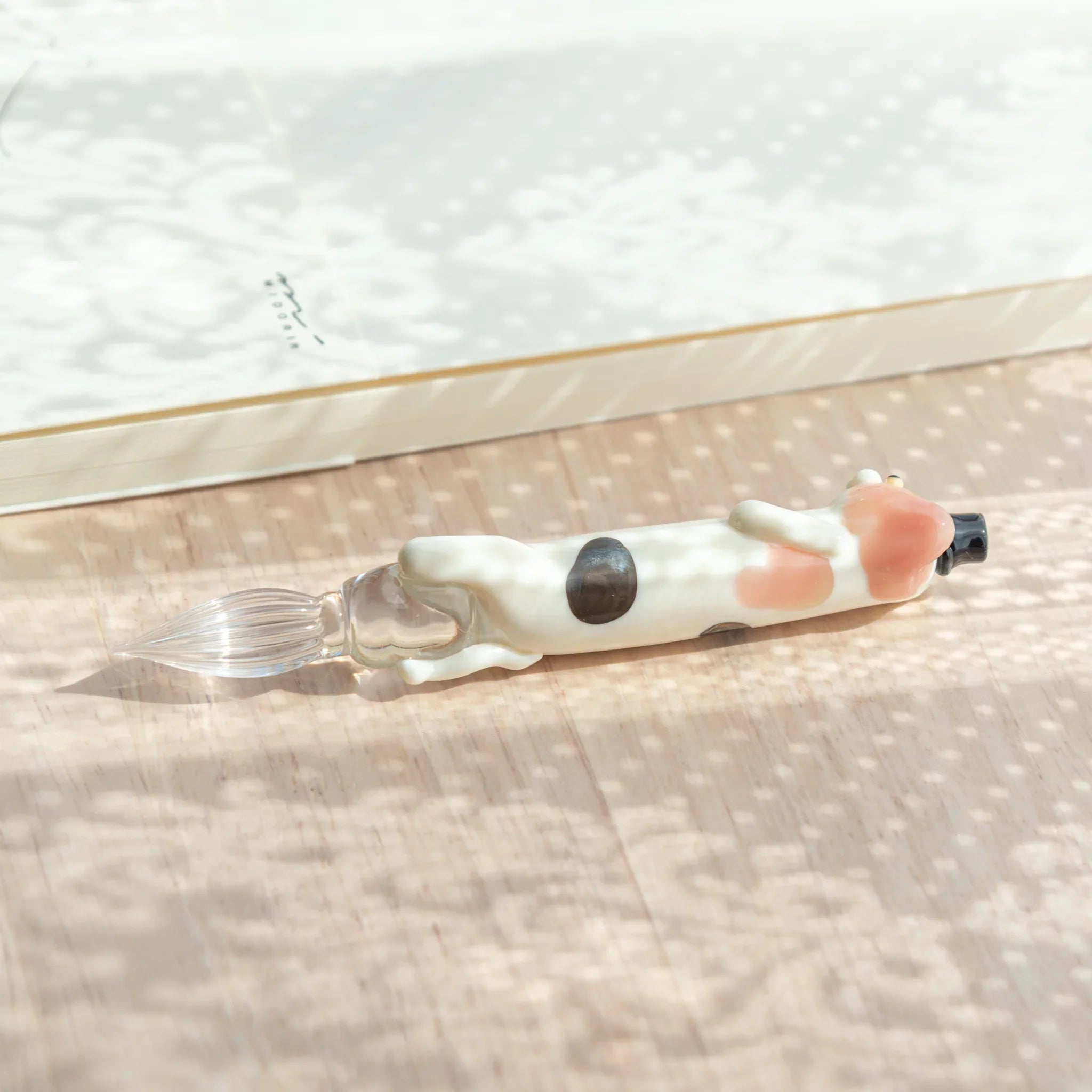 Glass dip pen featuring adorable spotted cat perched on colorful hand-blown glass ink bottle with style