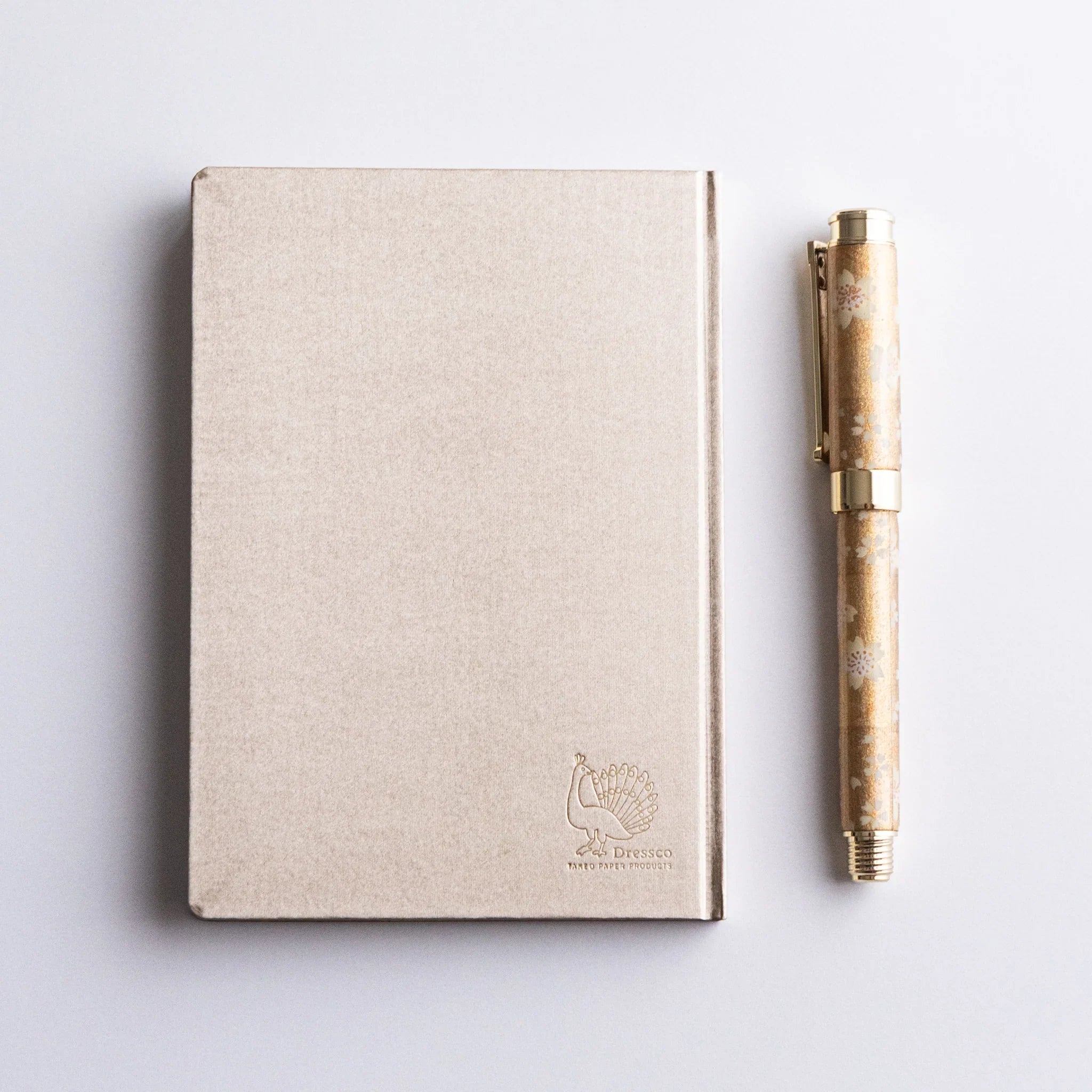 Dressco Bank Ledger Paper Japanese Notebook in Champagne Gold with a Japanese Fountain Pen beside.