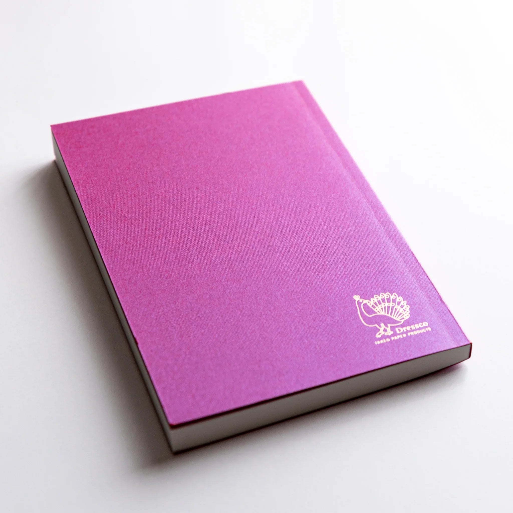 Dressco Pink Onion Skin Japanese Notebook A6 angled view with gold peacock logo embossed on the back cover.