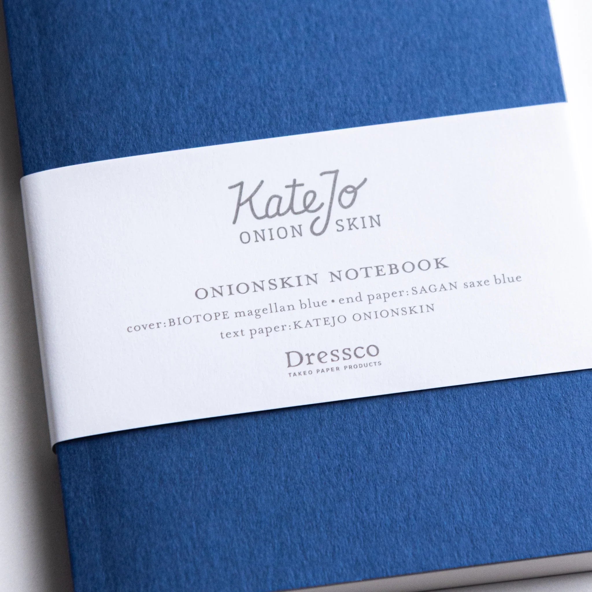 Close-up of Dressco Blue Onion Skin Japanese Notebook A6 with white band and minimalist typography.