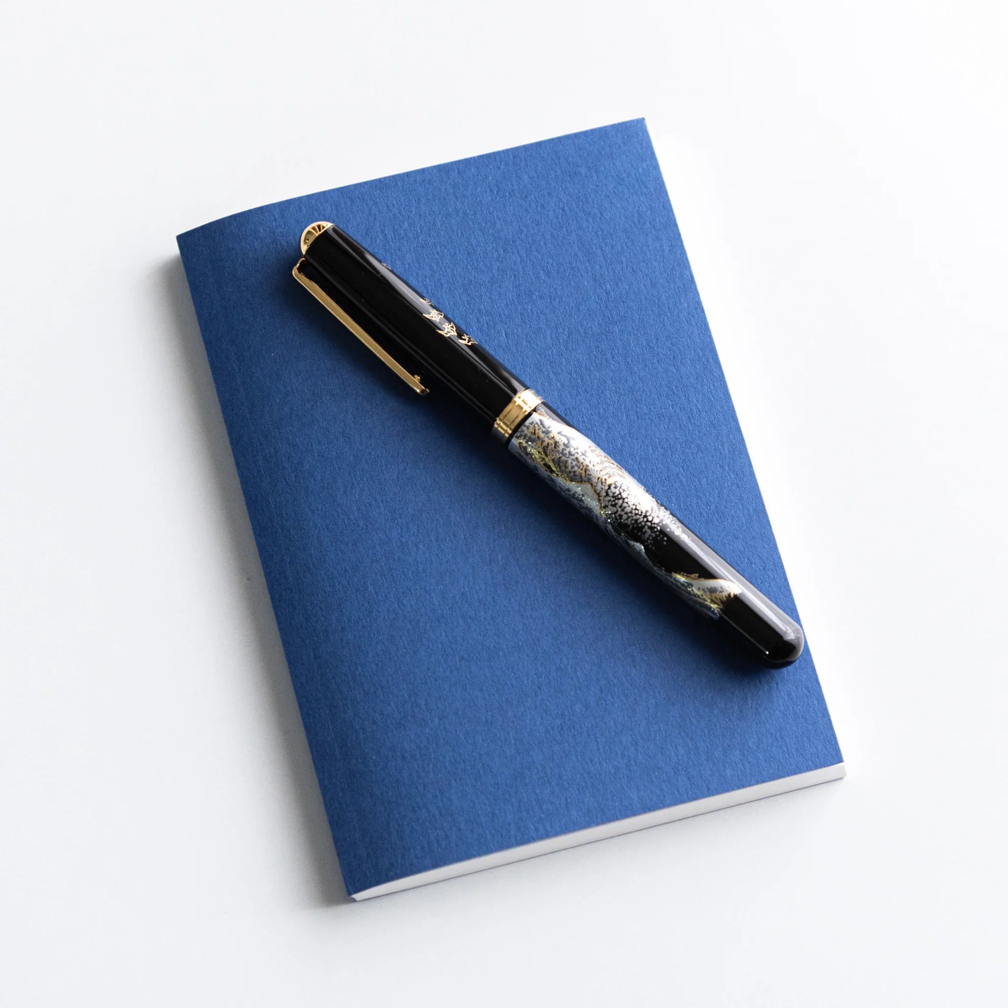 Black and gold Japanese Fountain Pen placed on Dressco Blue Onion Skin Japanese Notebook A6.