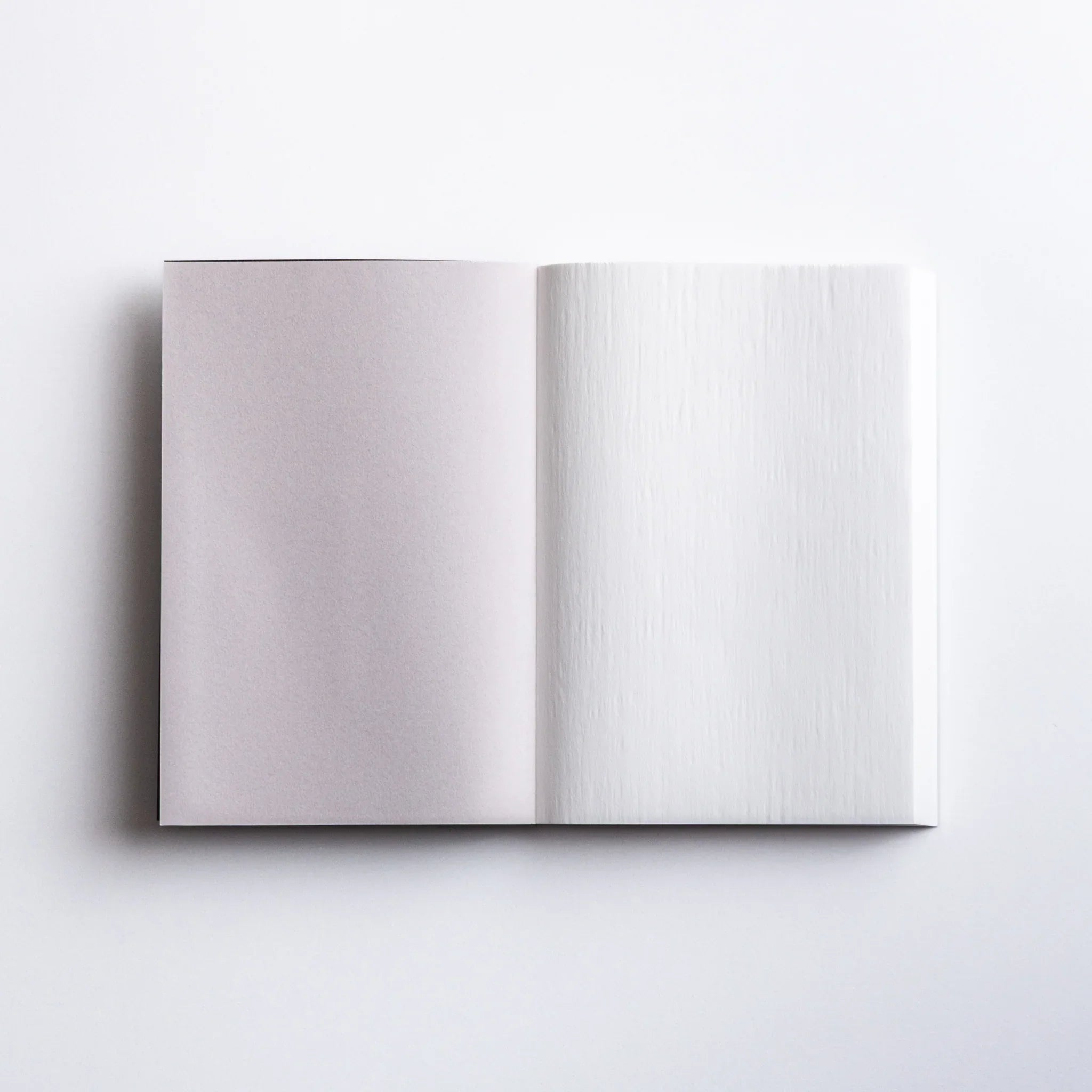 Open pages of Dressco Black Onion Skin Japanese Notebook A6 showing light gray and white sheets.