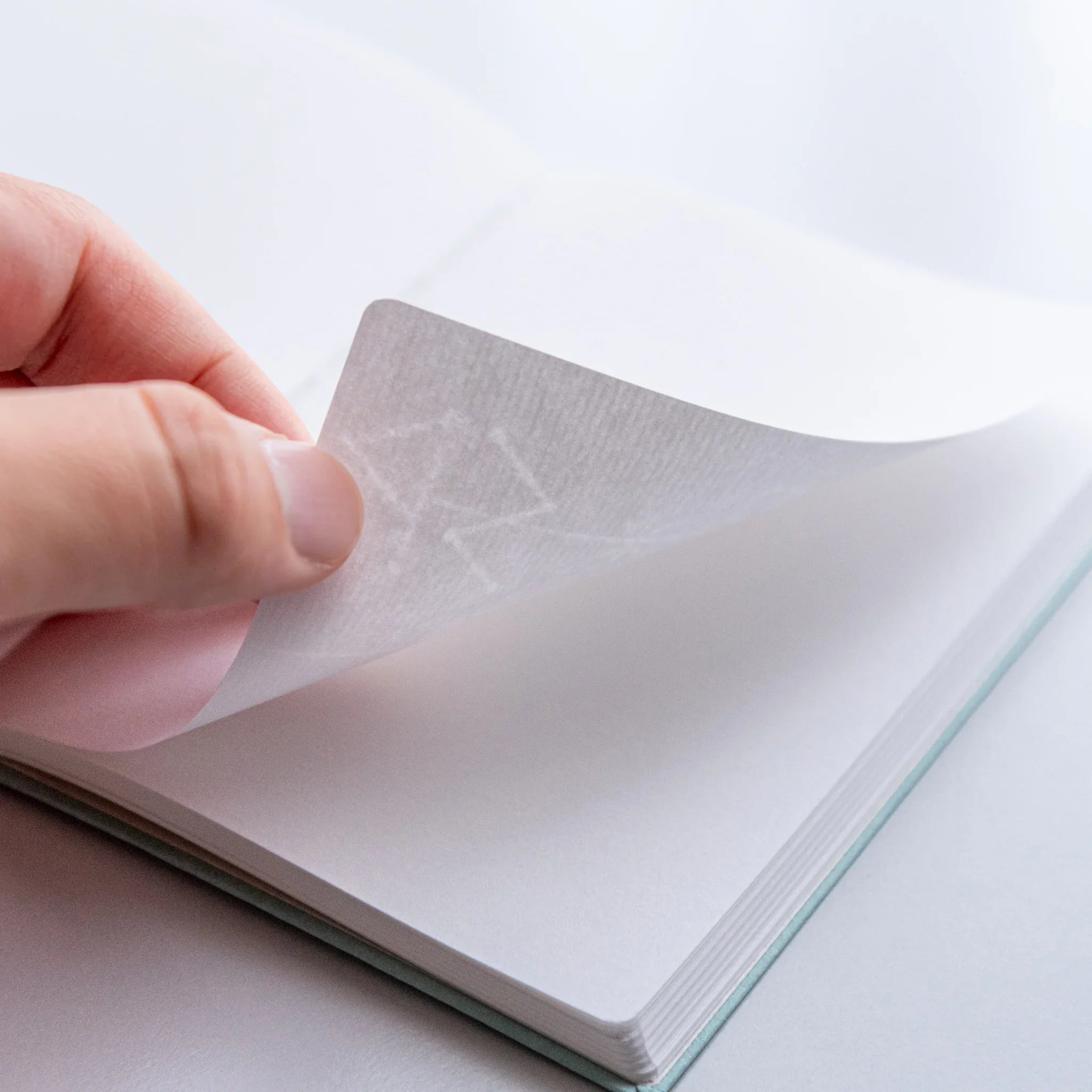 Dressco Spica Laid Bond Paper A6 notebook side view showing the book thickness and visible spine stitching detail