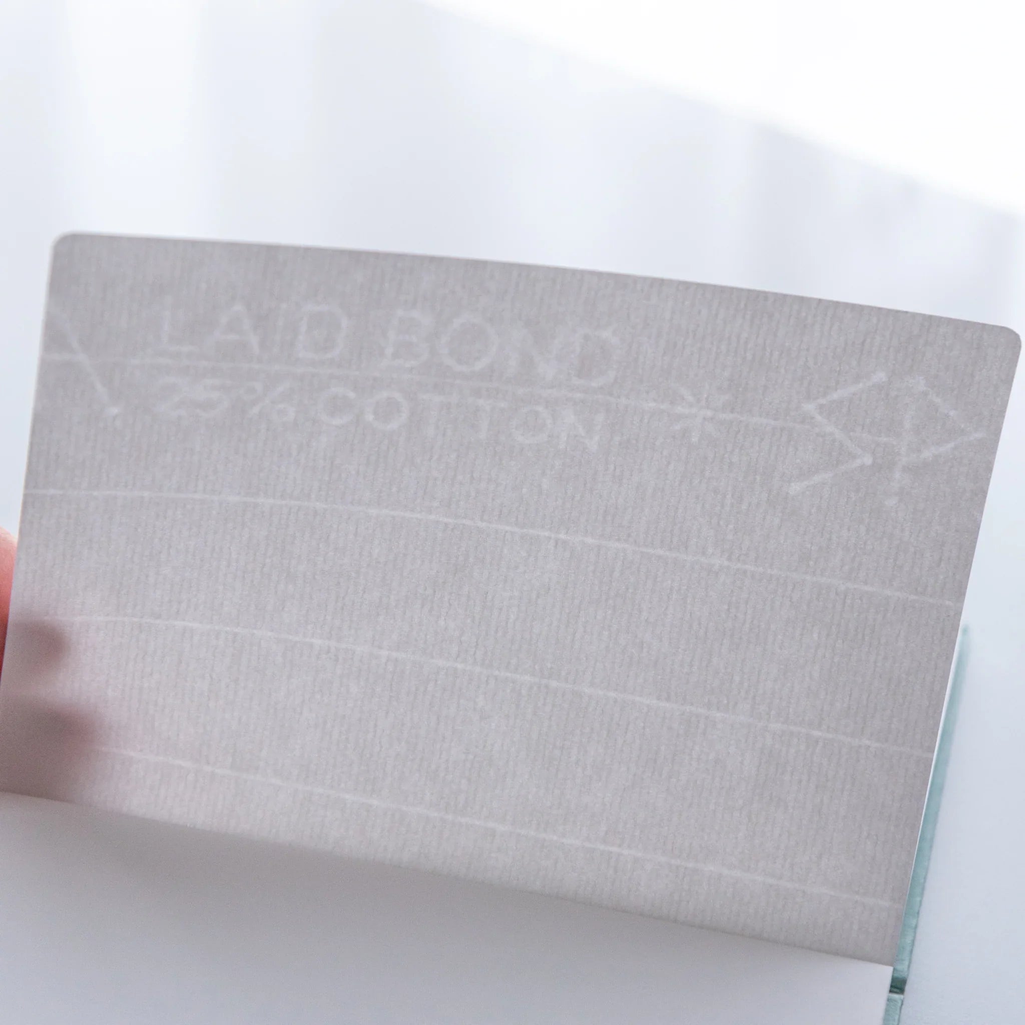 Dressco Spica Laid Bond Paper A6 notebook open to show interior pages with laid bond paper surface and ruling lines