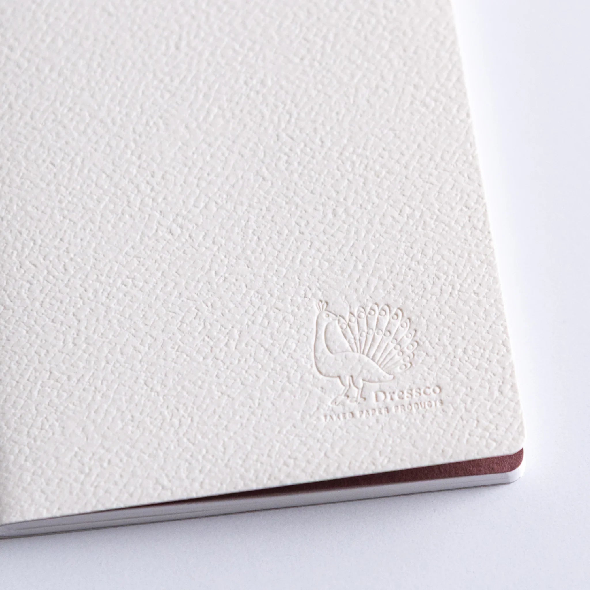 Dressco Spica Laid Bond Stitched A6 notebook placed cover-up showing the notebook cover and stitched binding edge