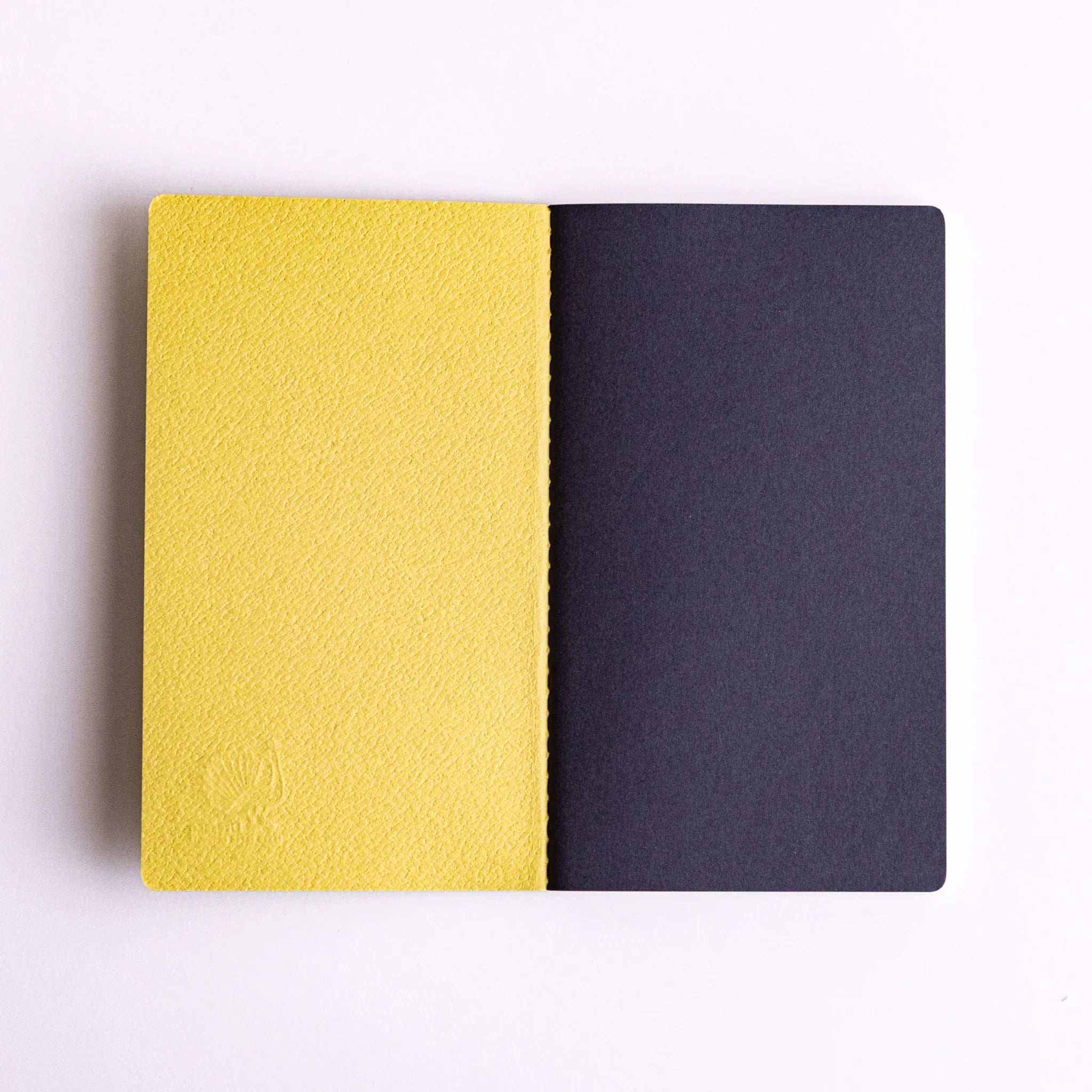 Side-by-side view of Japanese notebooks made from Spica Laid Bond Paper (avocado) and Bank Ledger Paper (gray), showcasing textured covers.