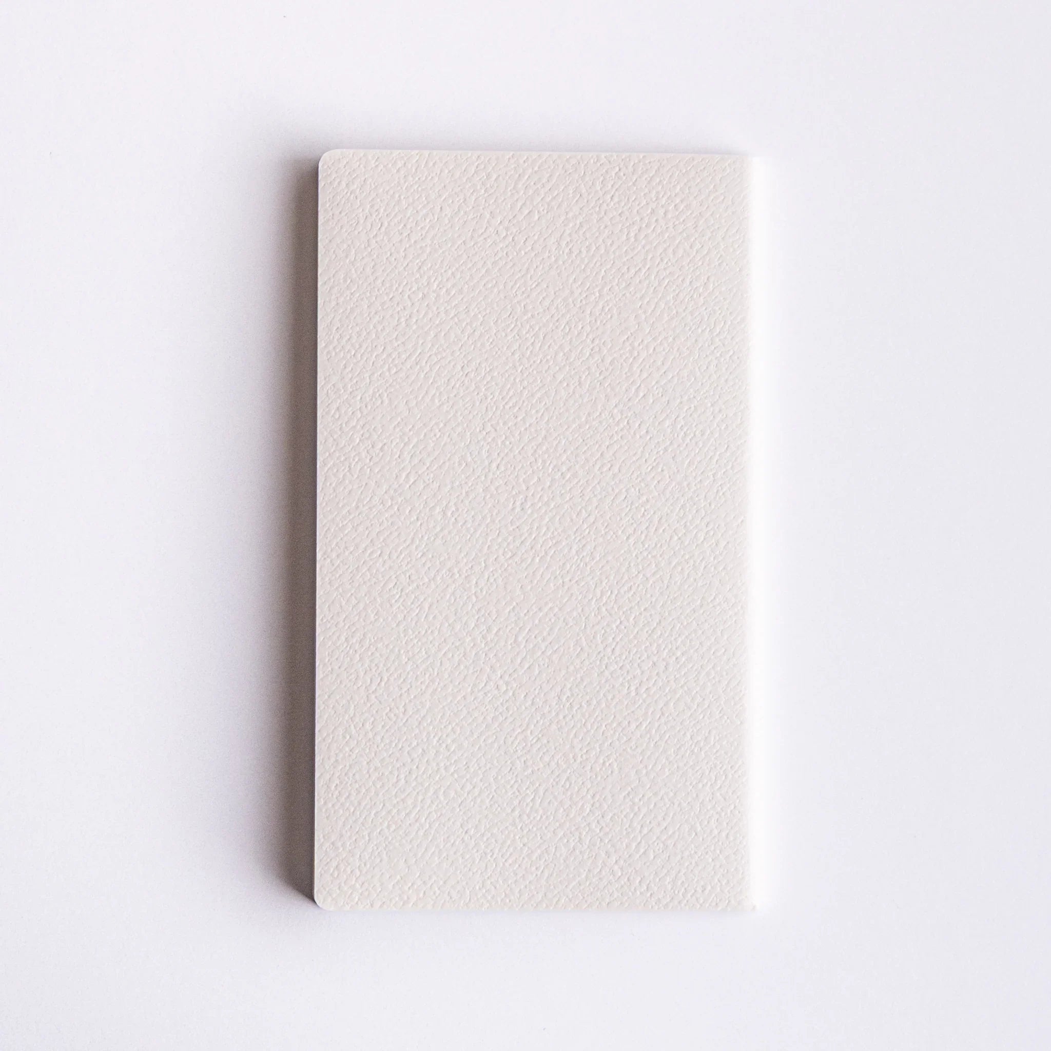 Minimalist Japanese notebook made with Spica Laid Bond Paper, featuring a textured white cover and stitched binding.