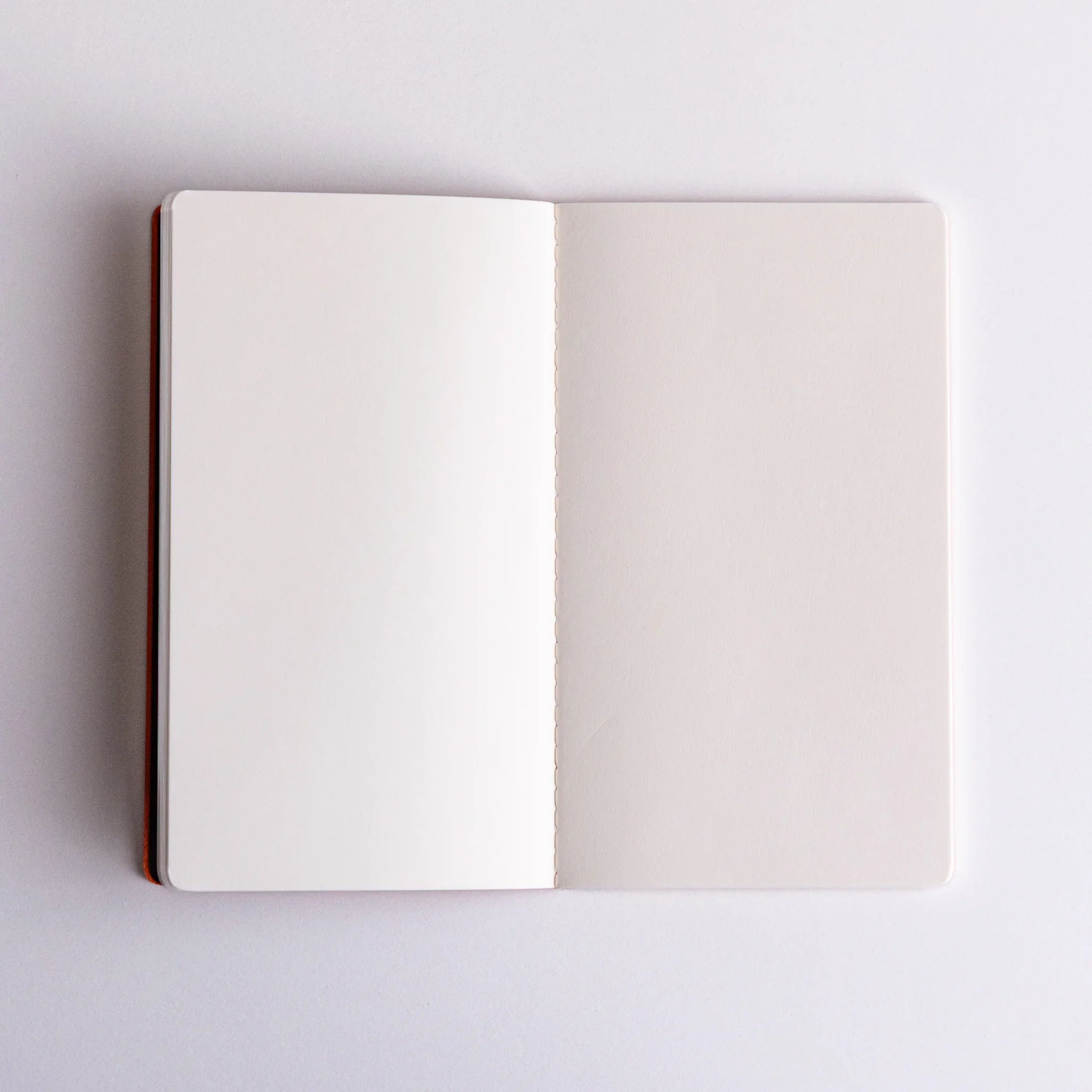 Open Japanese notebook made from bank ledger Paper, displaying pristine blank pages and stitched binding.