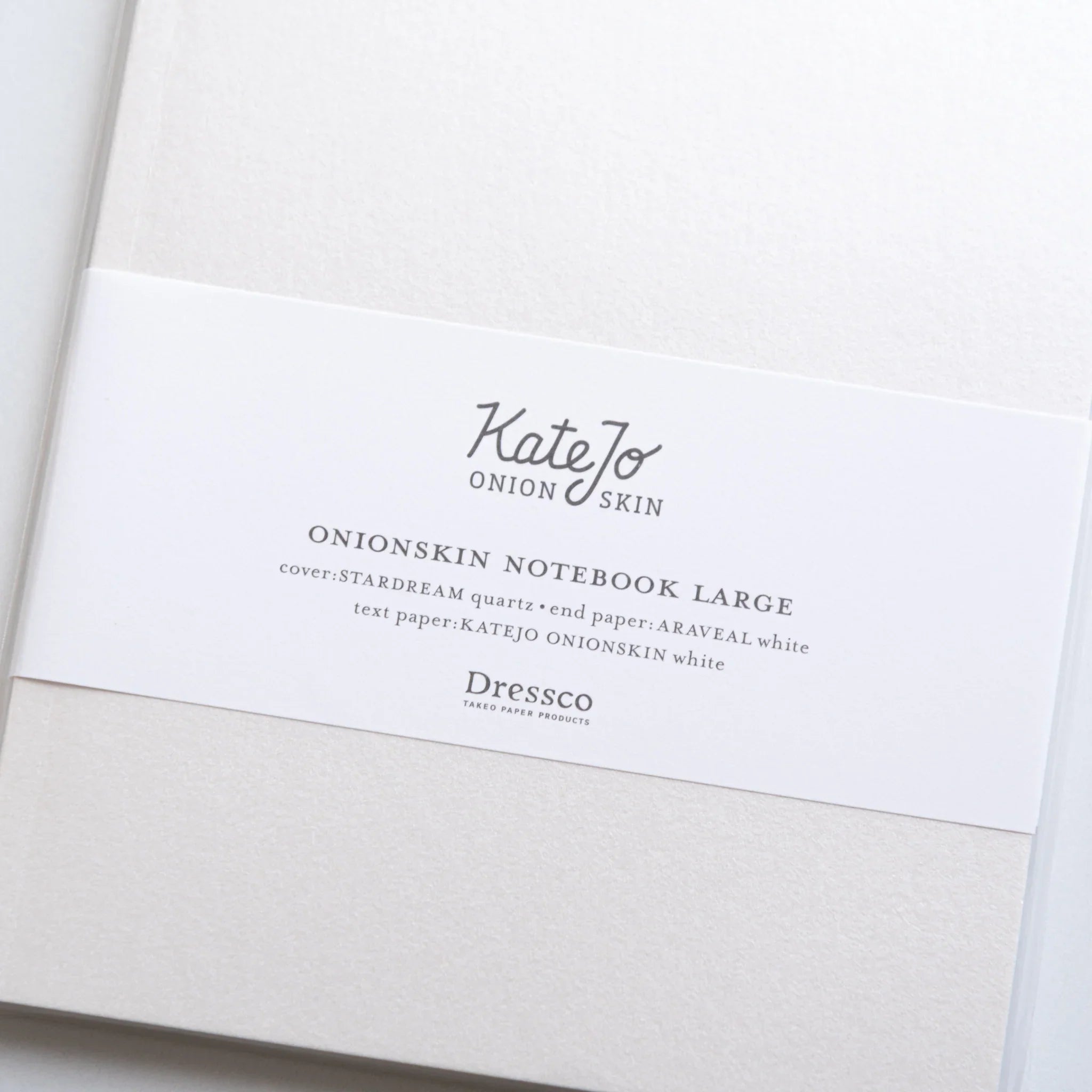 Close-up of Dressco White Onion Skin Japanese Notebook B6 band, showing product title and elegant texture.