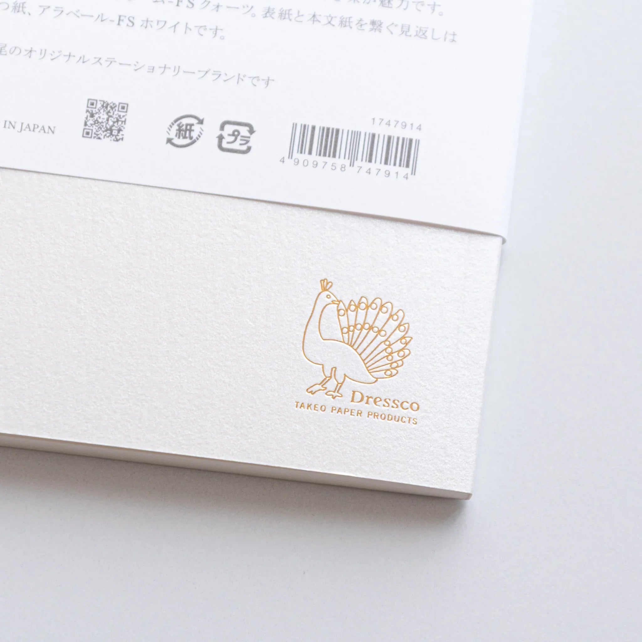 Close-up of Dressco White Onion Skin Japanese Notebook B6 back label with gold Dressco peacock logo.