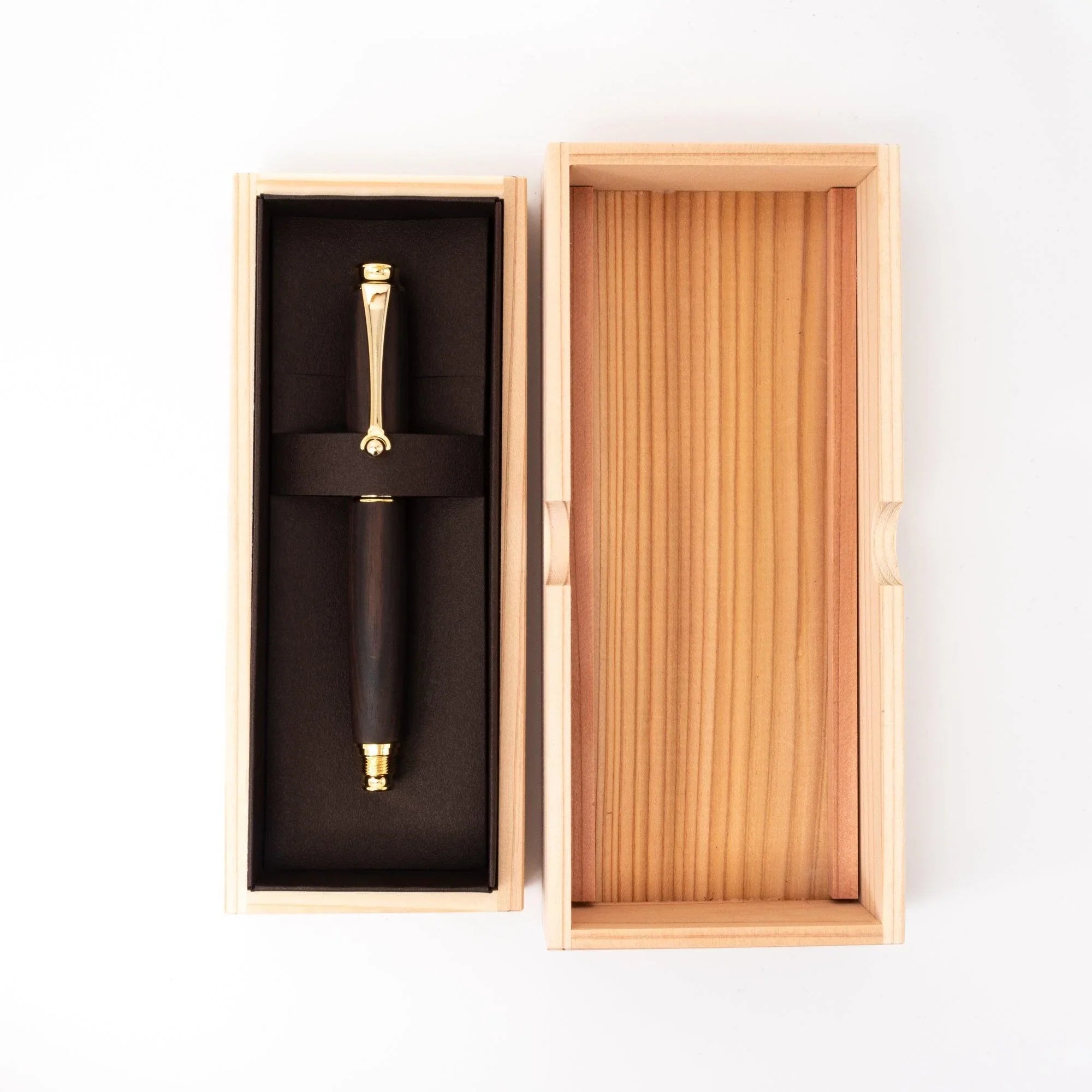 Ebony wood Japanese fountain pen in open wood gift box with black lining, lid open showing ribbed interior, overhead view