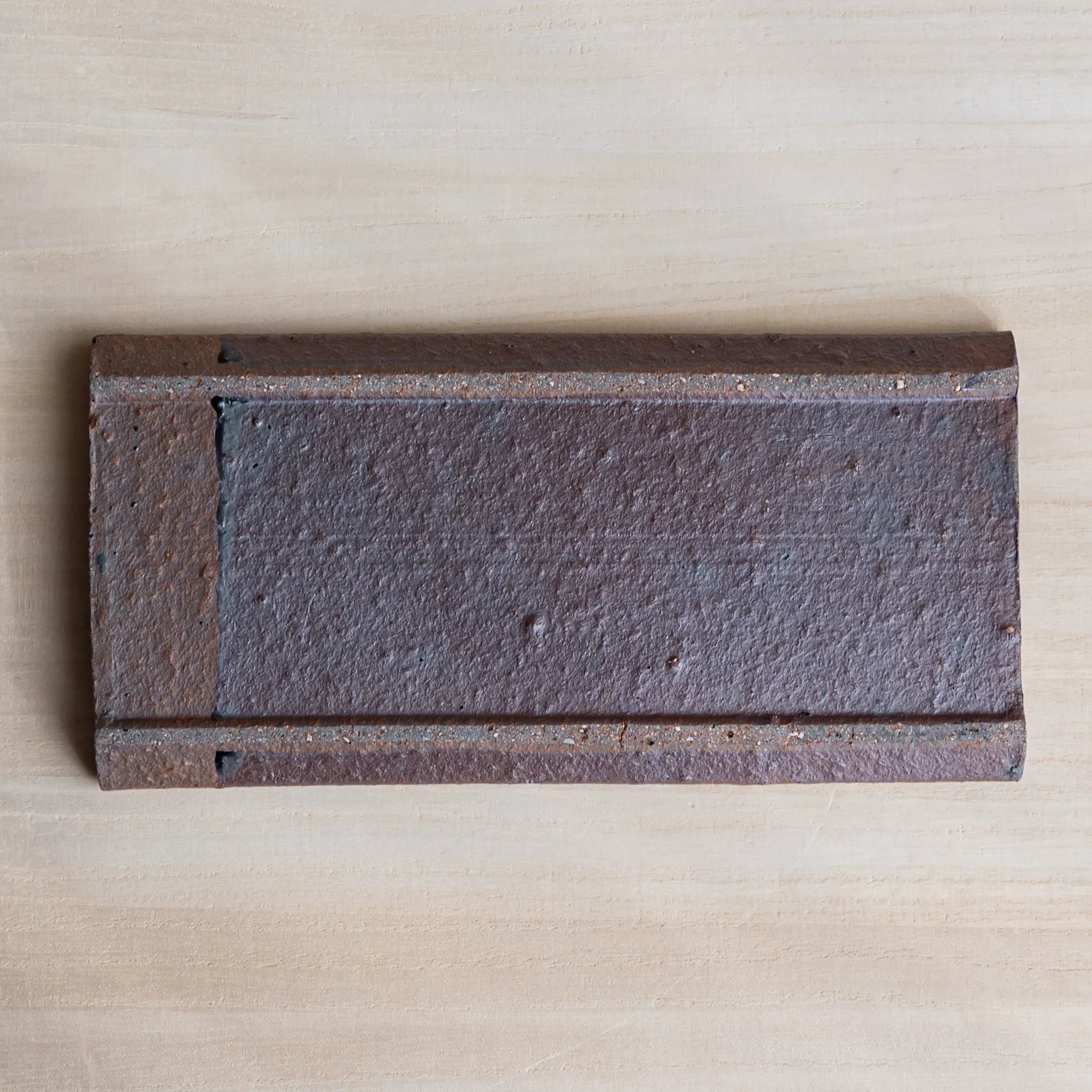 Japanese Pen Tray Desk Accessory top view of red ceramic pen tray showing textured surface and grooves on light wooden desk.
