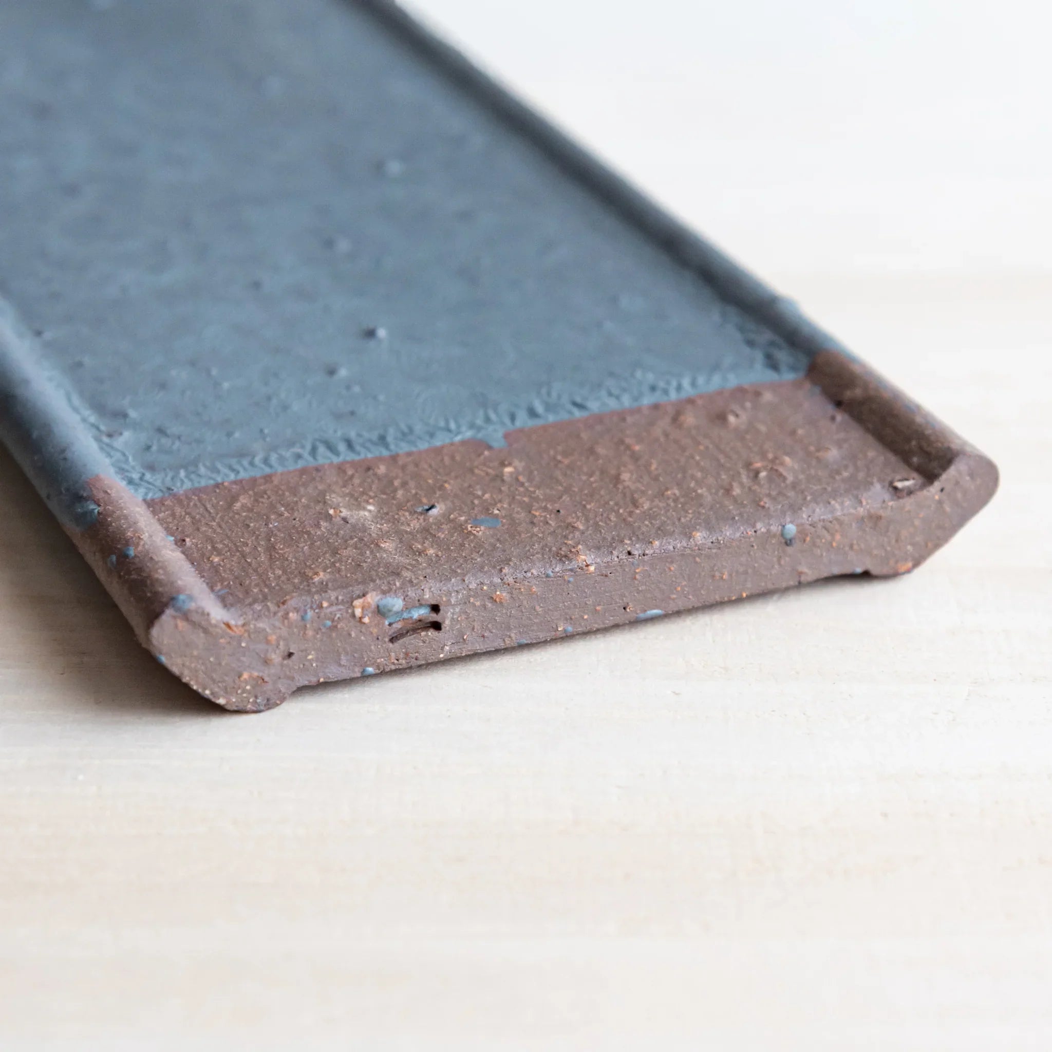 Japanese Pen Tray Desk Accessory showing close-up angled view of silver gray ceramic tray with brown end on light wood.