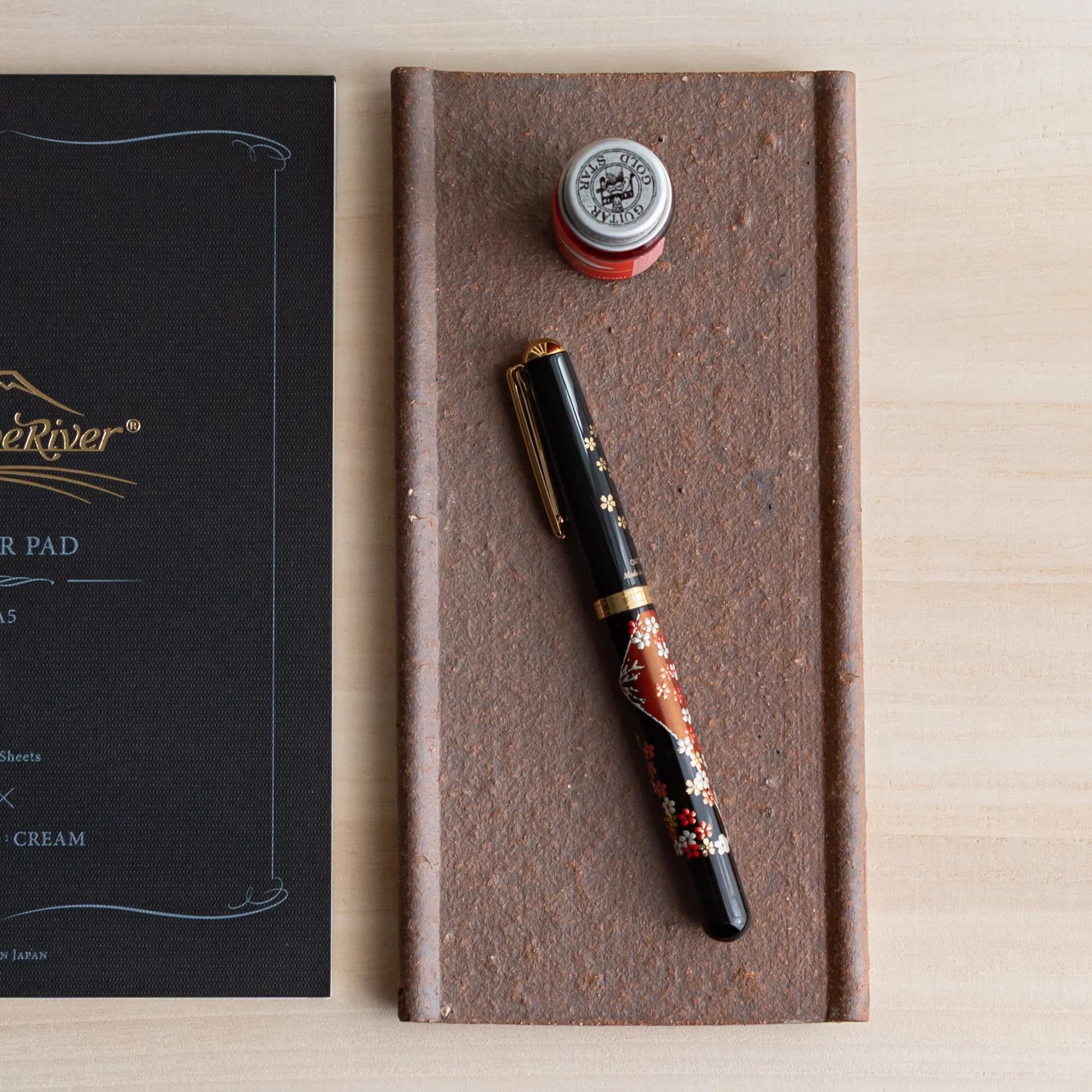 Japanese Pen Tray Desk Accessory with yakishime clay ceramic tray beside a Tomoe River paper pad, holding a fountain pen.