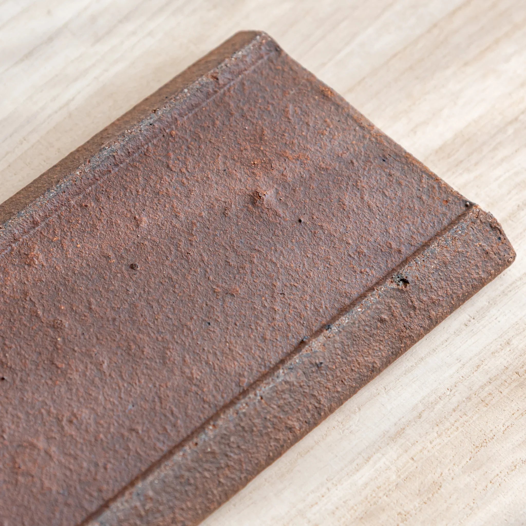 Japanese Pen Tray Desk Accessory close-up texture view of yakishime clay ceramic tray surface on wood desk.