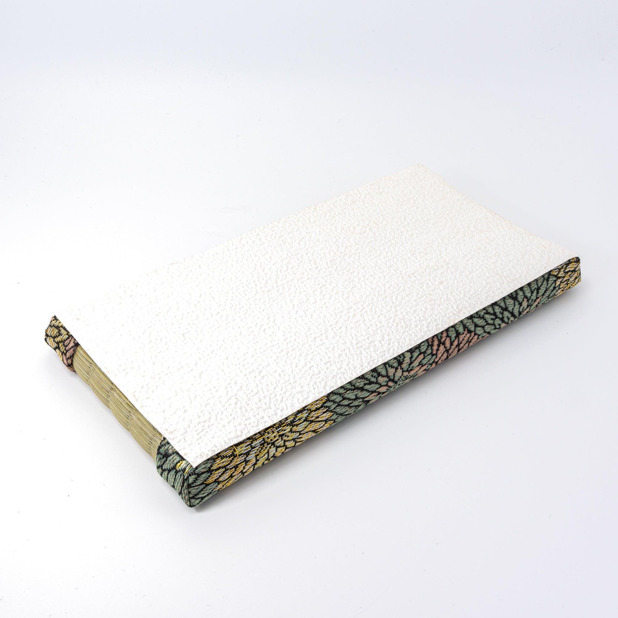 Underside of a tatami pen tray covered in textured white material, bordered with floral-patterned fabric, highlighting refined Japanese stationery design.