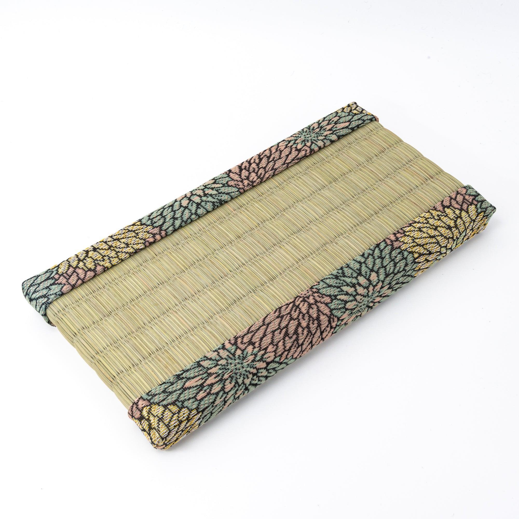 Angled view of a tatami pen tray with floral-patterned edges, emphasizing its natural material and use in presenting Japanese stationery.