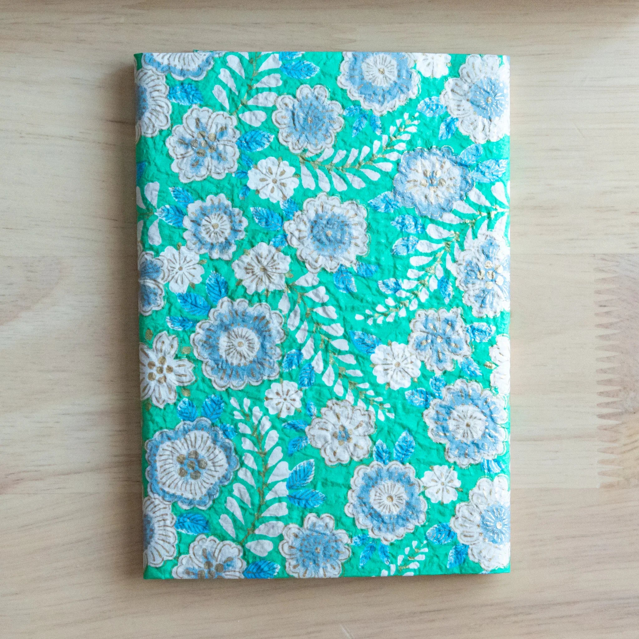 Emerald green hand-dyed yuzen washi book cover A6, closed front view with white and blue flower embossed pattern