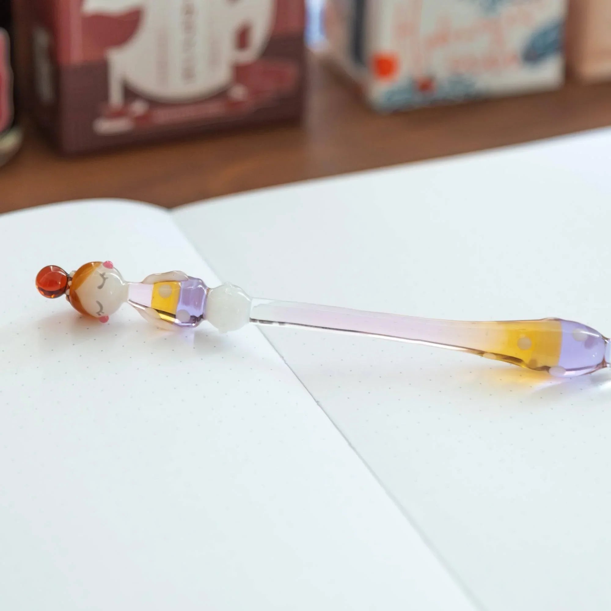 Fashionable Lady Marun-Chan glass dip pen with polka-dot decorated bulb positioned on white paper desk