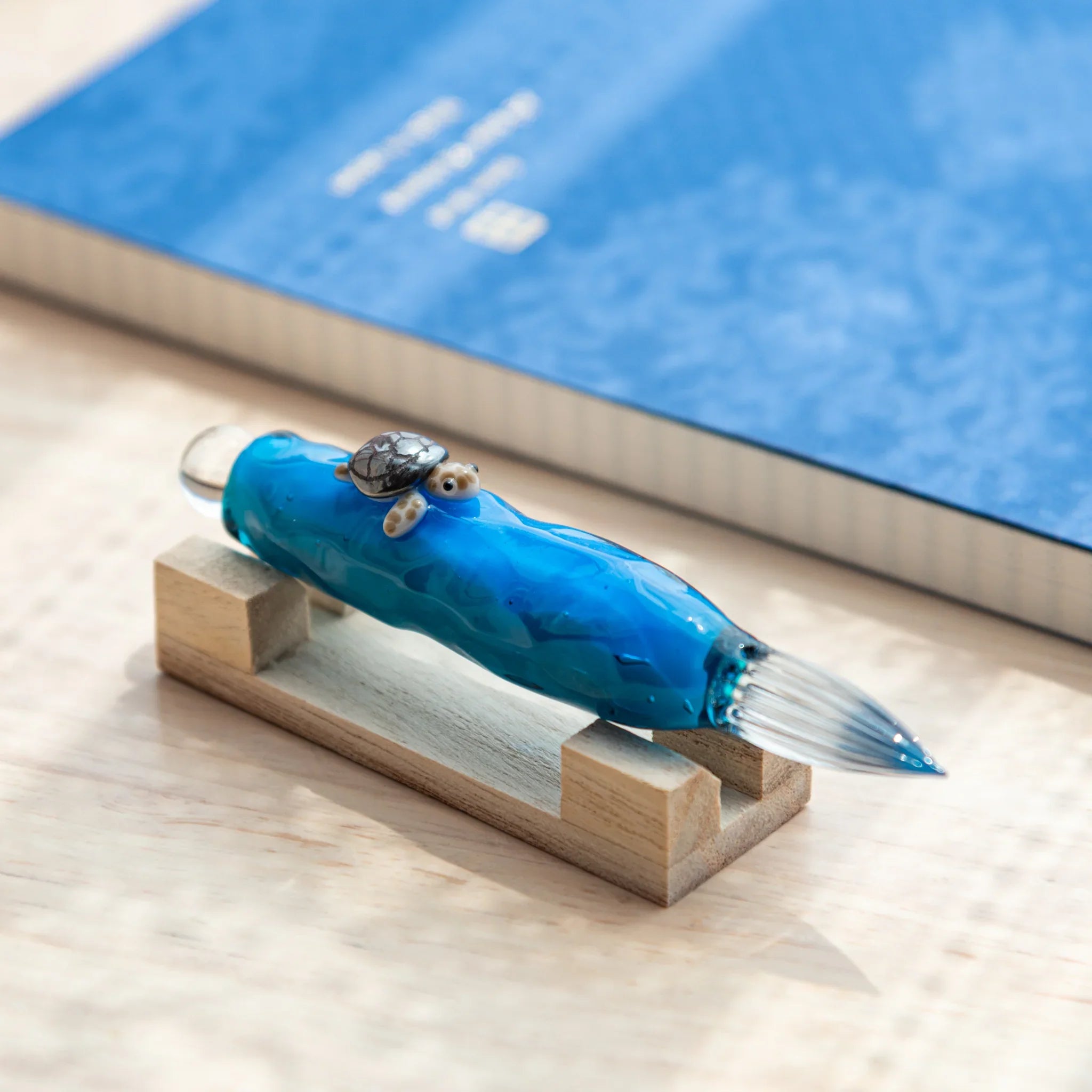 Floating Sea Turtle Japanese Glass Dip Pen with blue ocean-inspired body and detailed turtle design on wooden pen rest.
