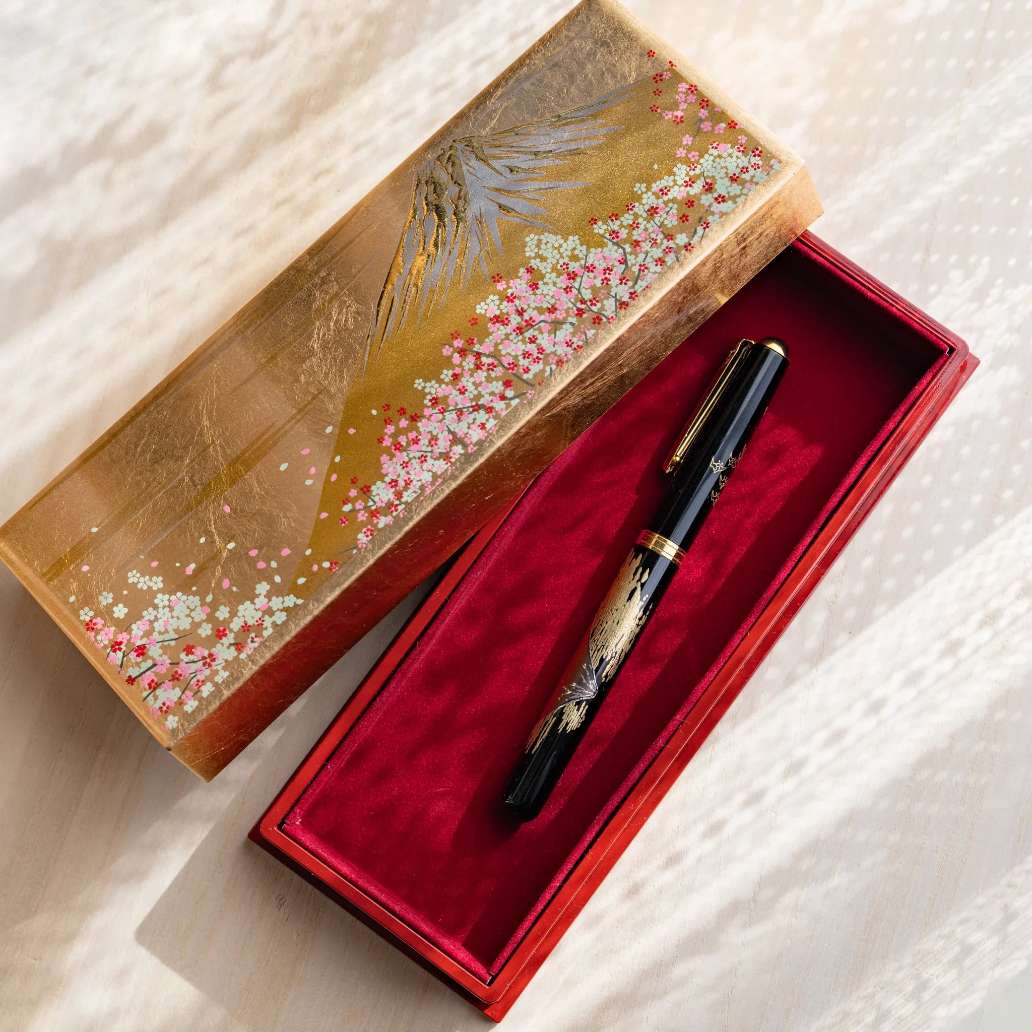 Gold colored pen case opened revealing compartmented interior structure for pen storage displayed clearly