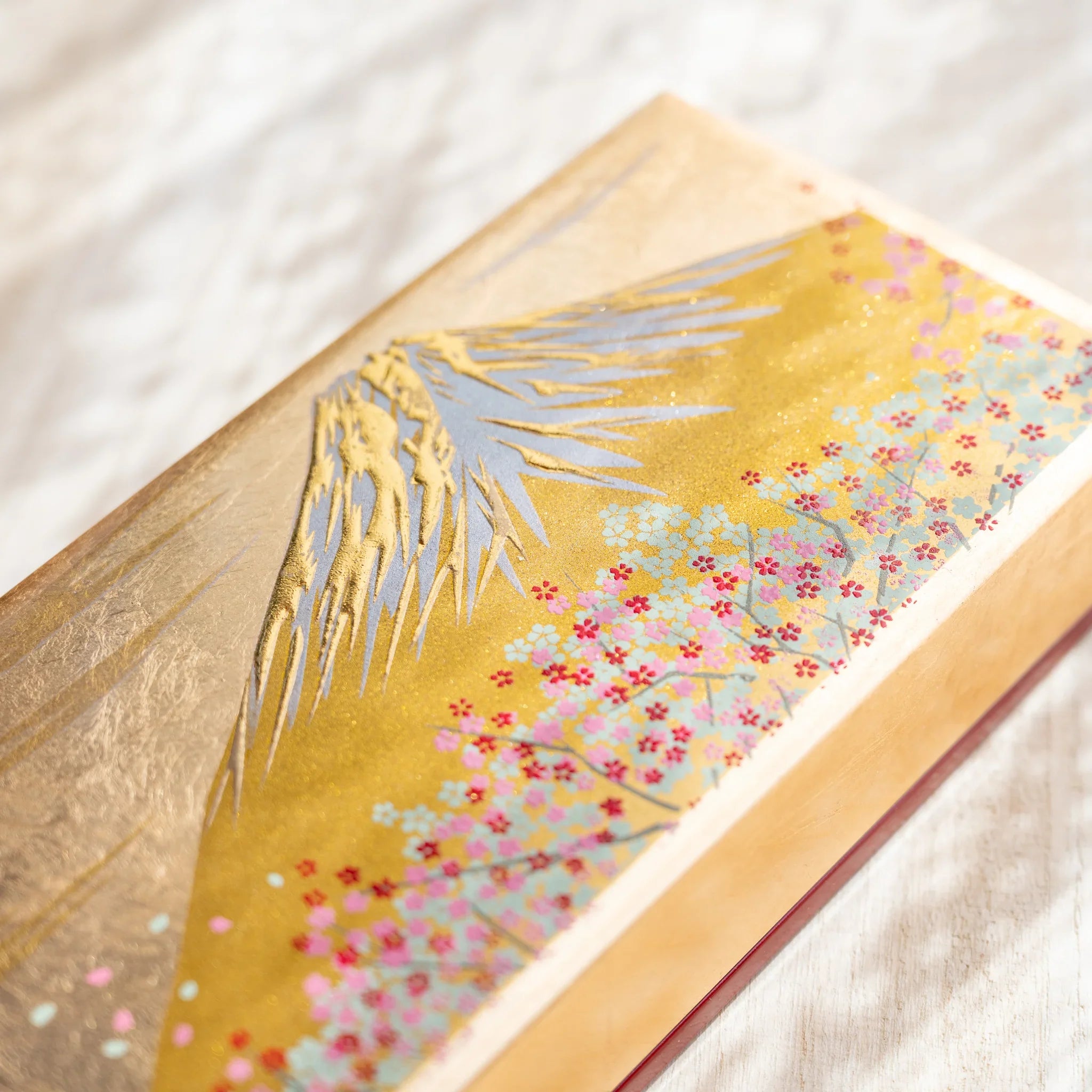 Japanese pen case shown closed with gold-toned lid featuring Mount Fuji and cherry blossoms in a full top view