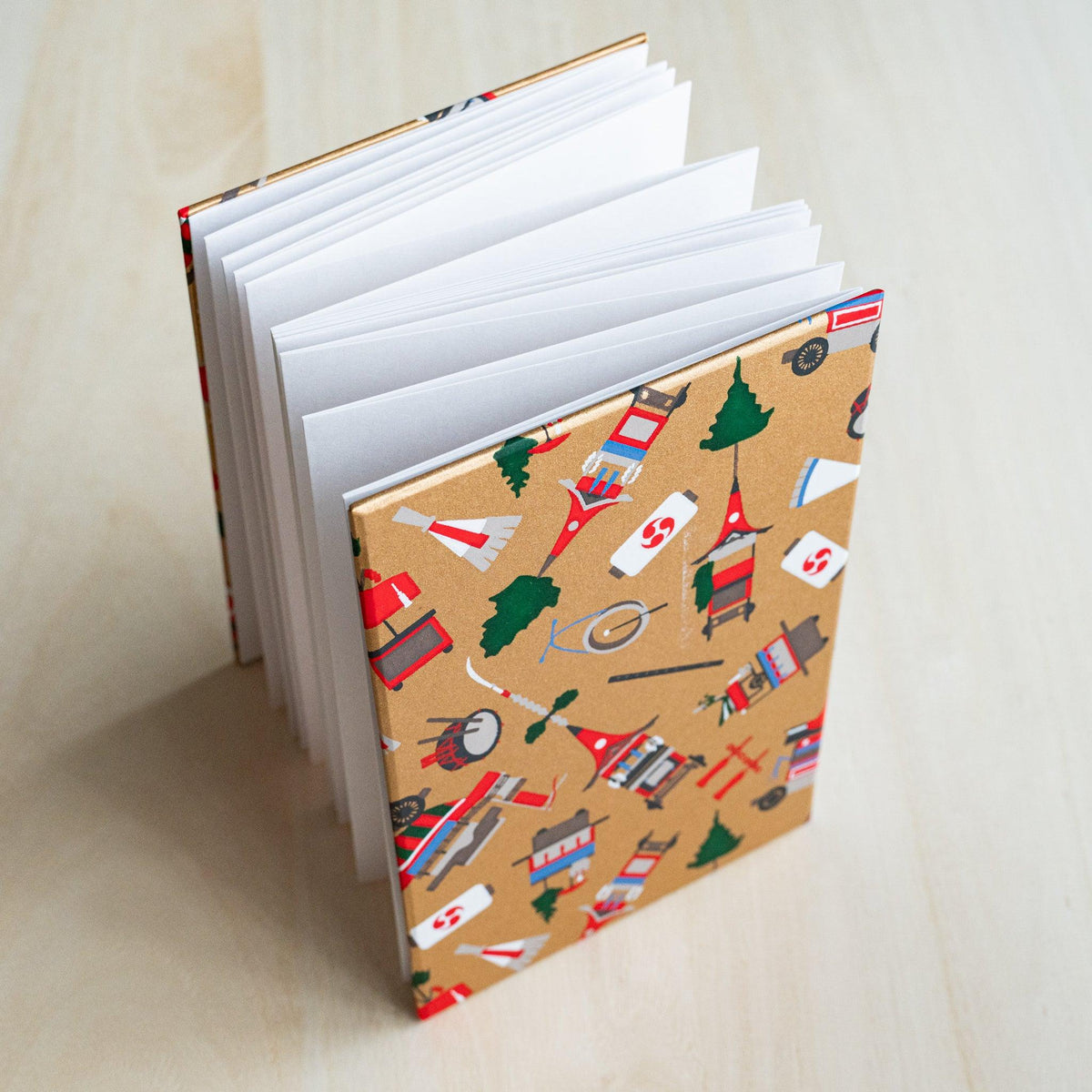 Gion Kyoto goshuincho stamp book standing open, accordion-fold white pages fanned out, gold cover