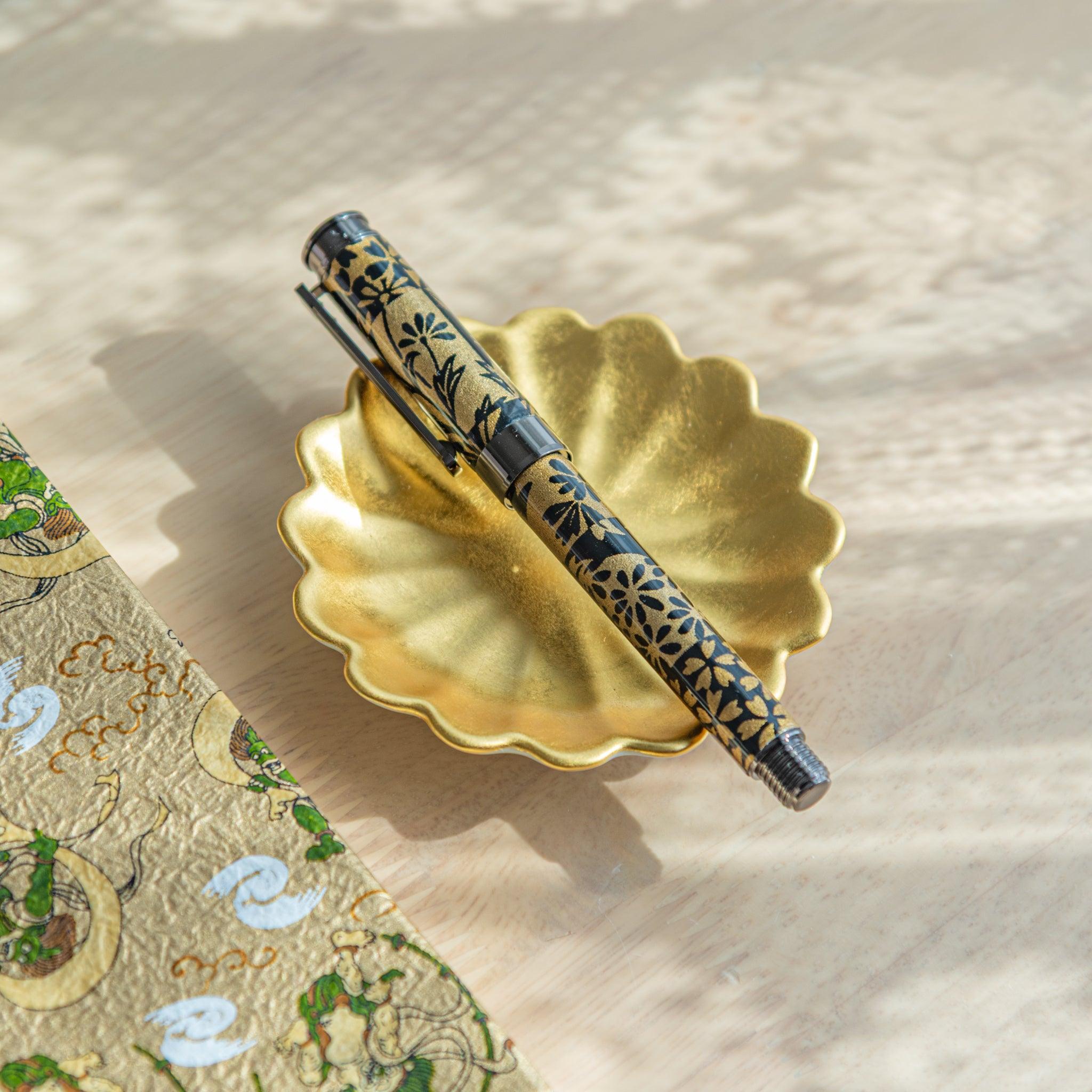 A Japanese stationery fountain pen, resting on a gold pen rest.