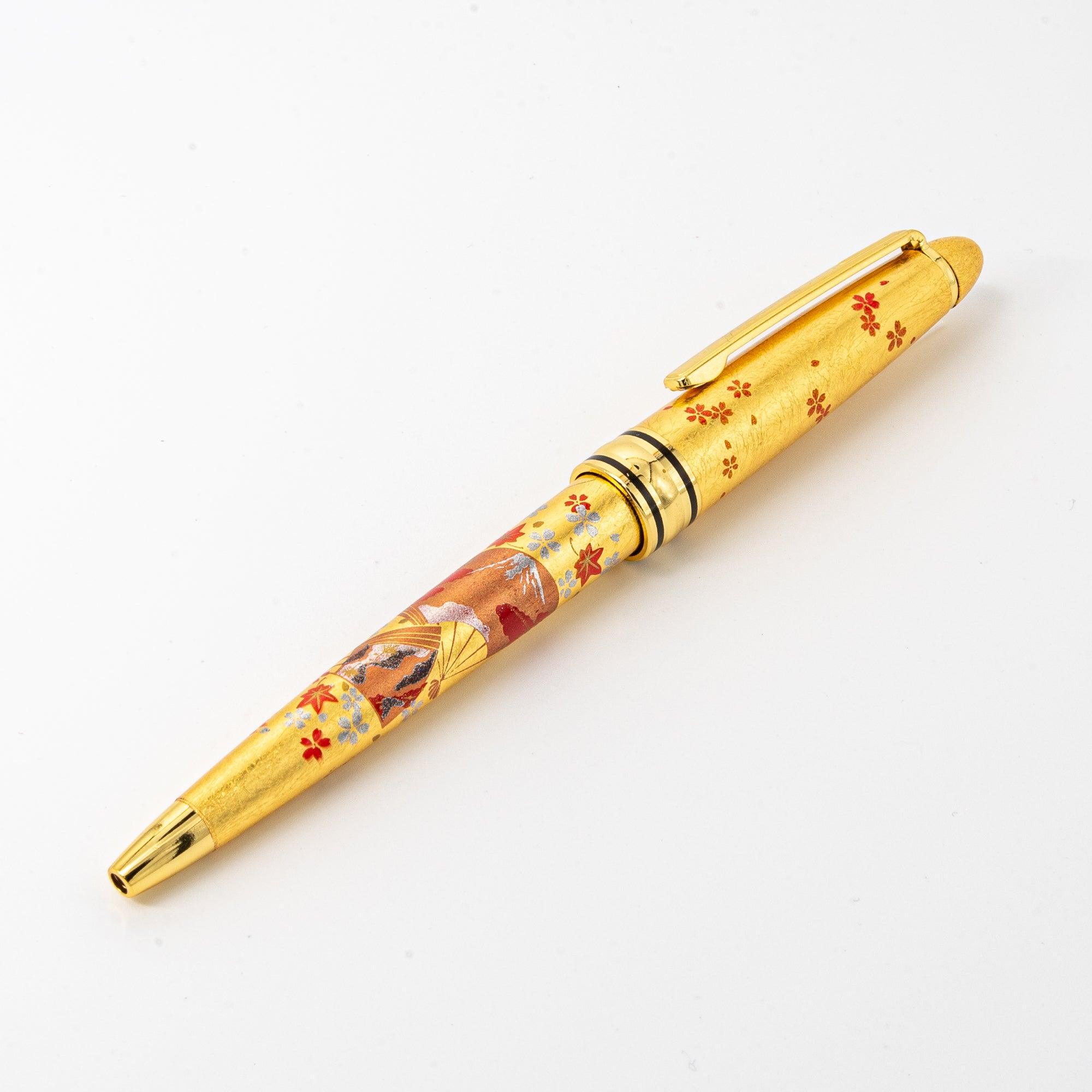 A detailed view of the gold maki-e ballpoint pen showcasing its intricate Japanese fan design and polished gold finish.
